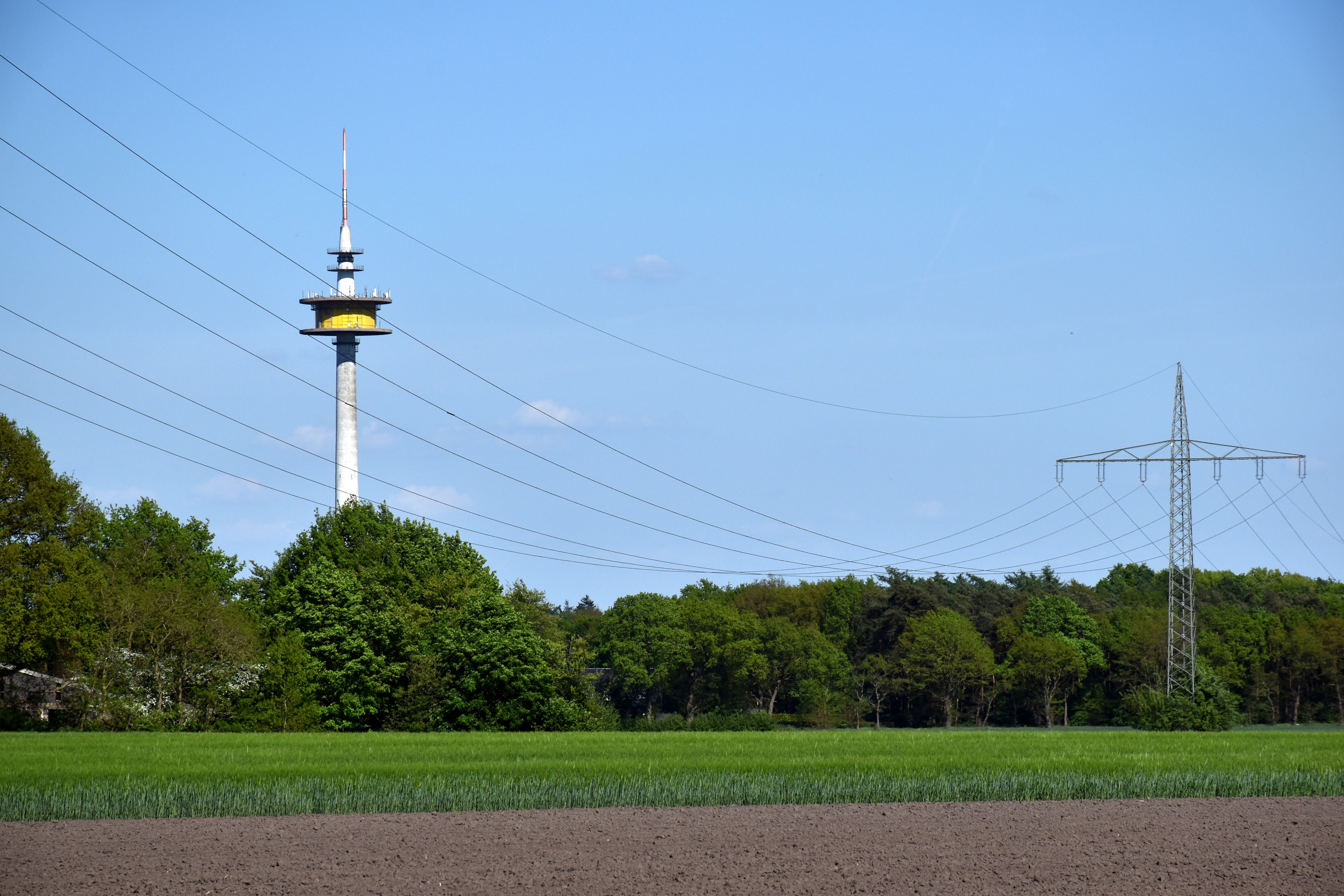 A tall communication tower stands near power lines.