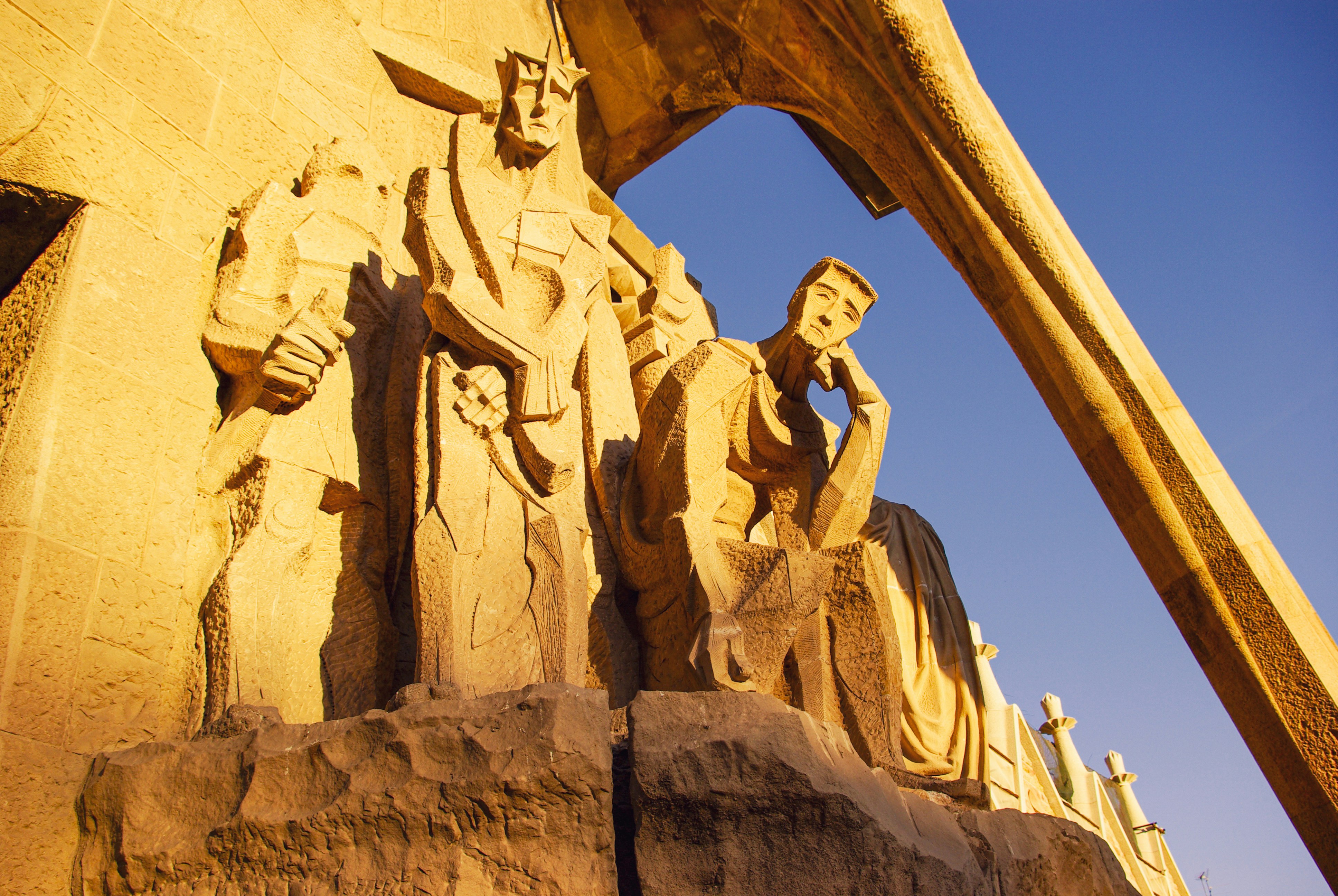 Stone sculptures on a building facade under blue sky.