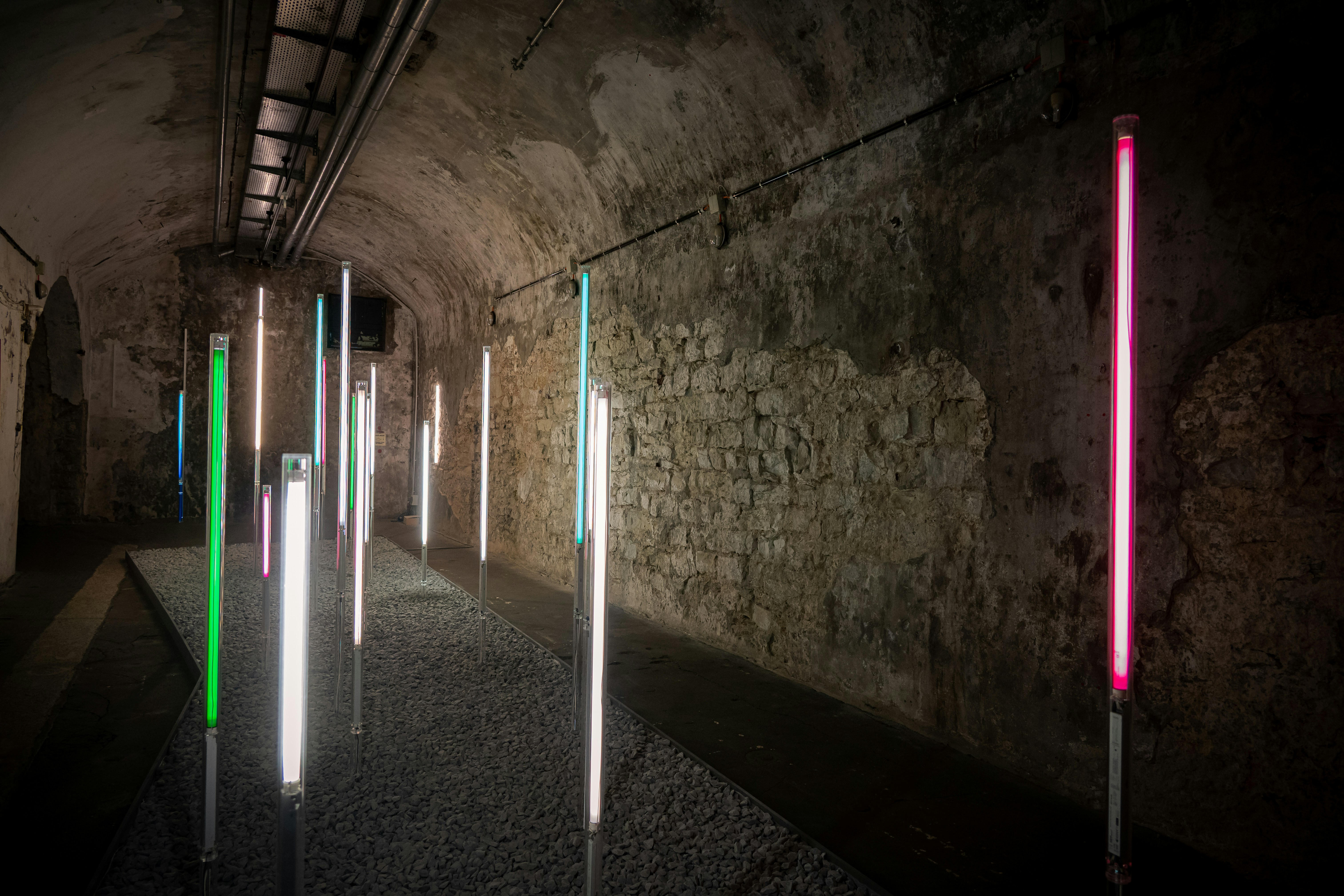 Colorful lights illuminate a stone tunnel walkway