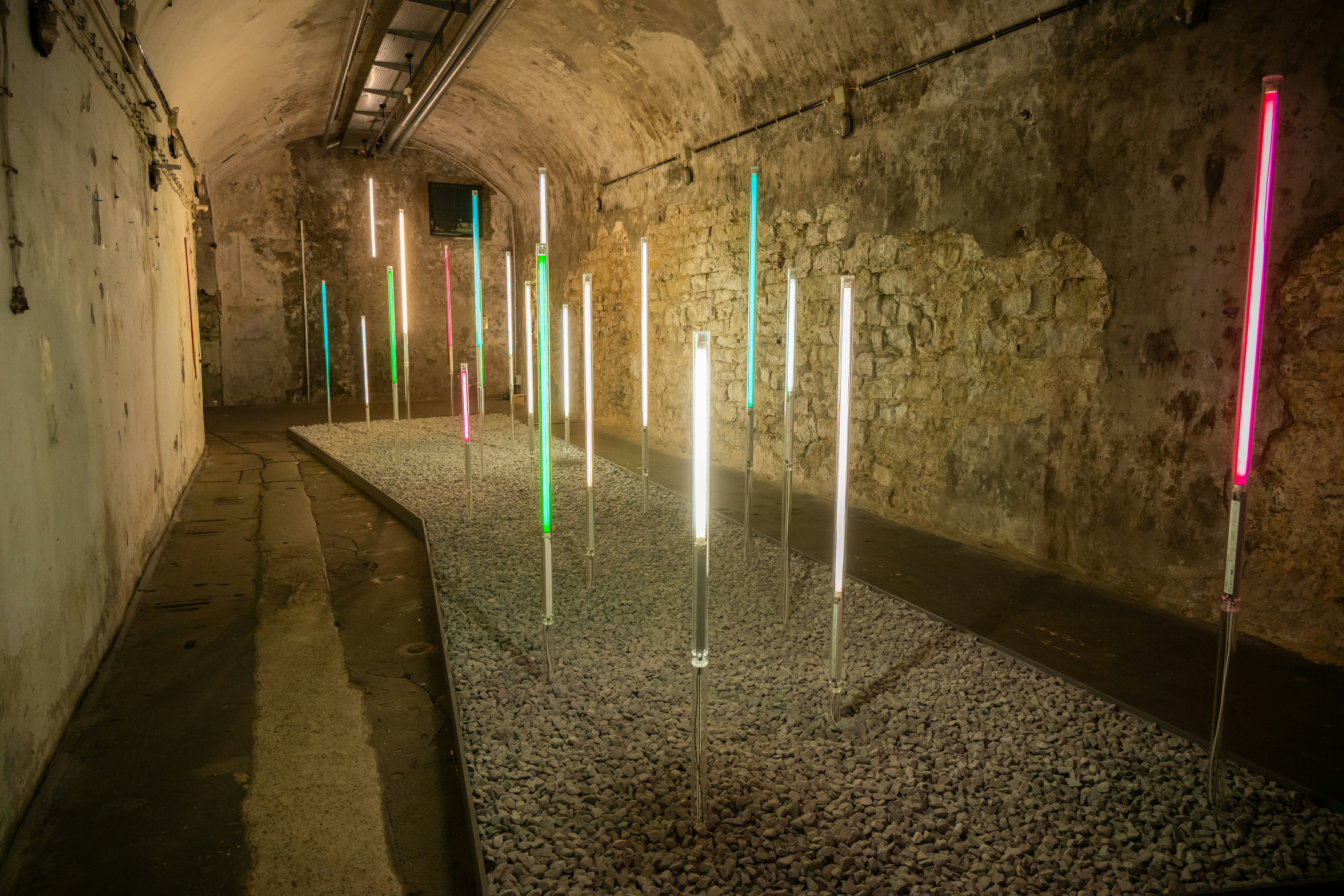 Colored lights illuminate a gravel-filled tunnel space.