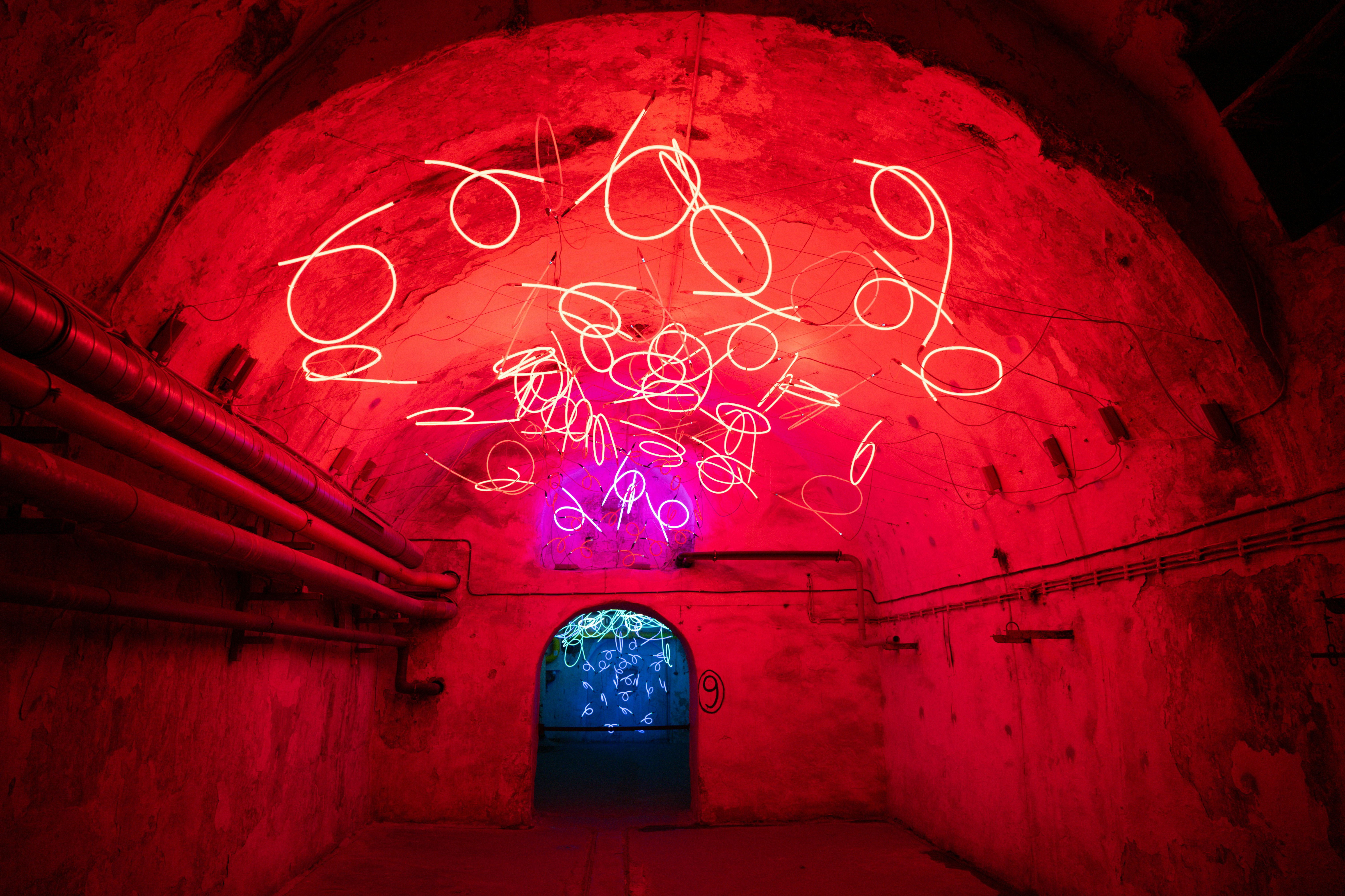 Neon art installation in a red-lit tunnel