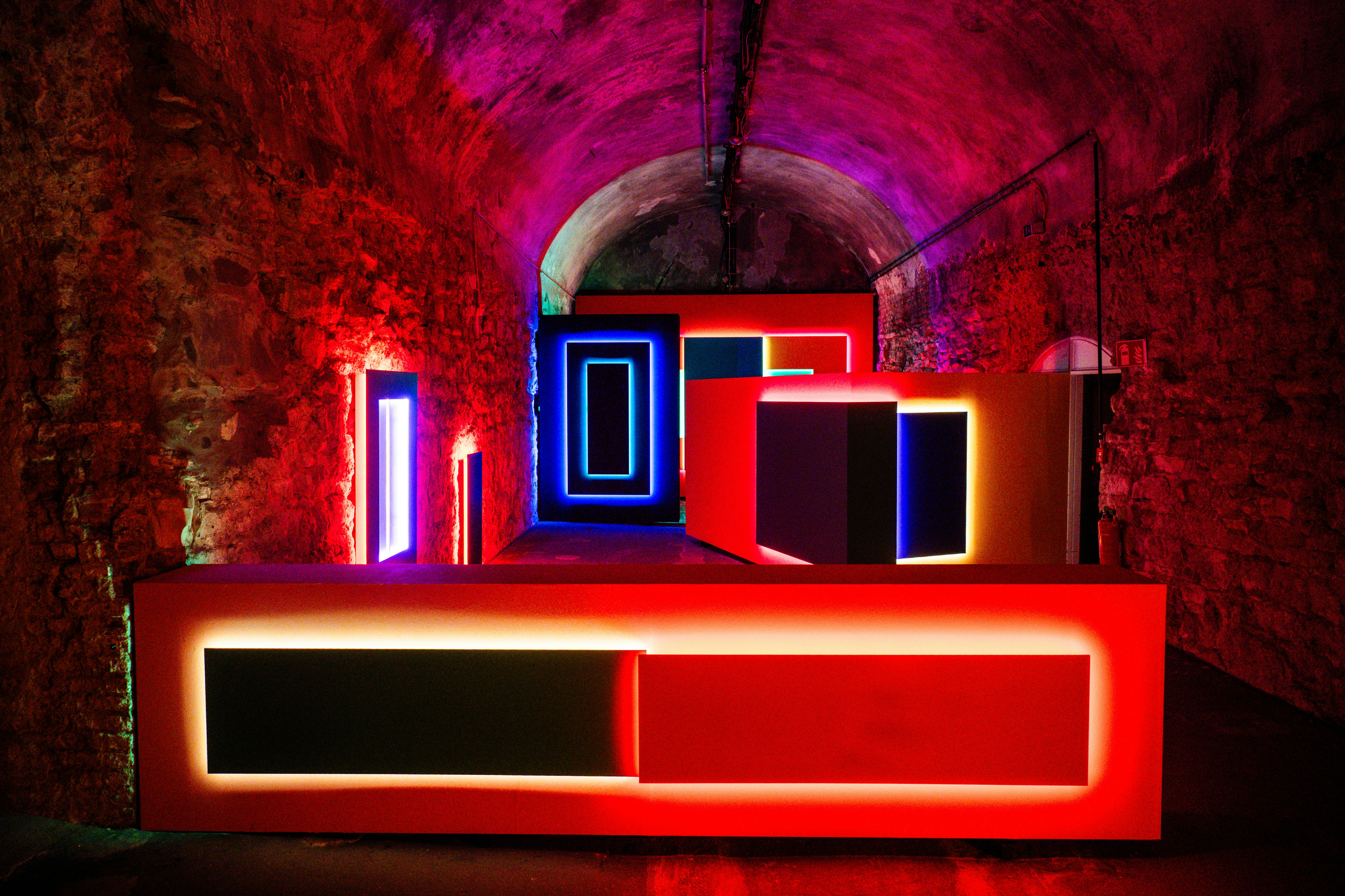 Illuminated geometric shapes in a tunnel with red lighting