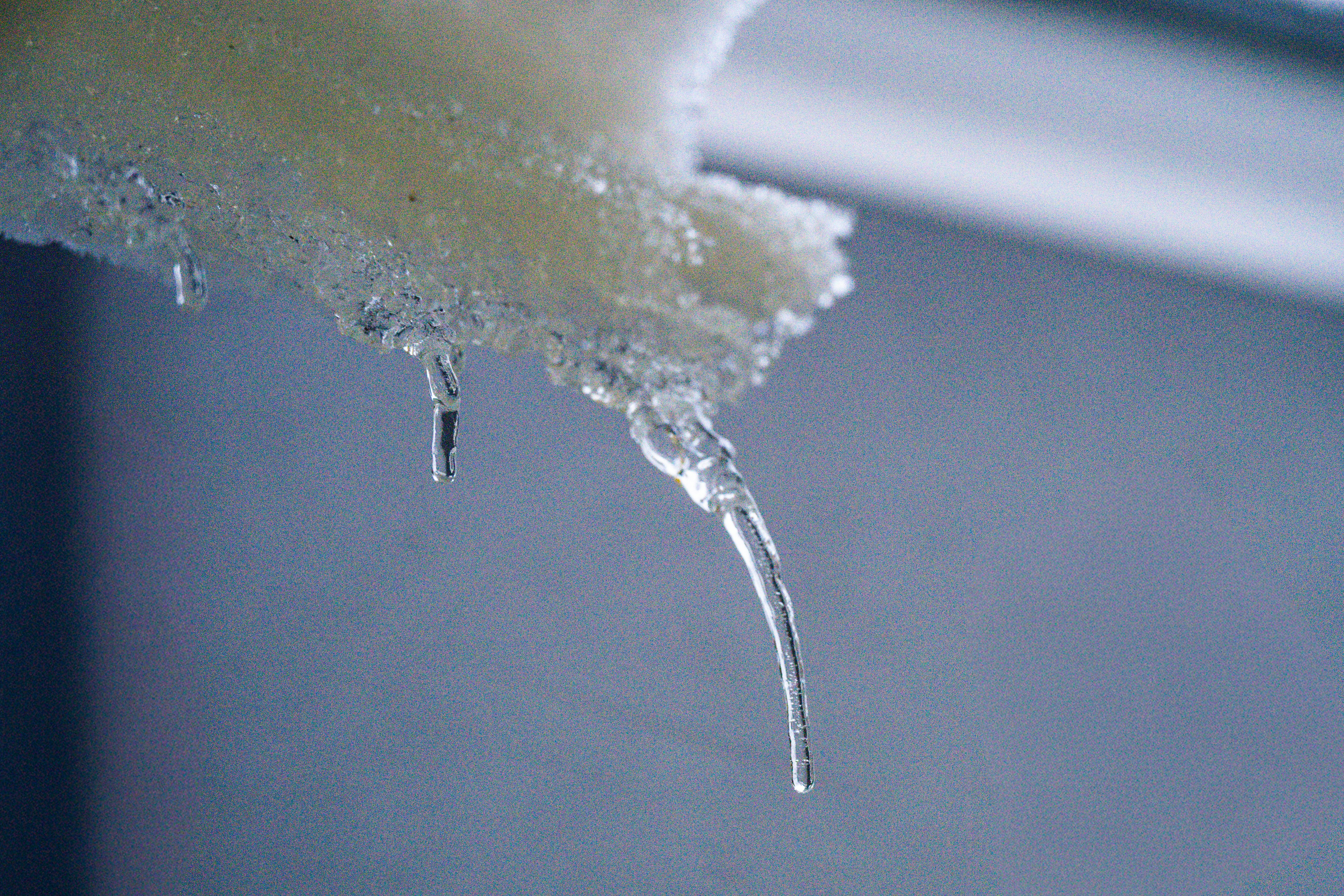 Melting icicles dripping from snow-covered ledge