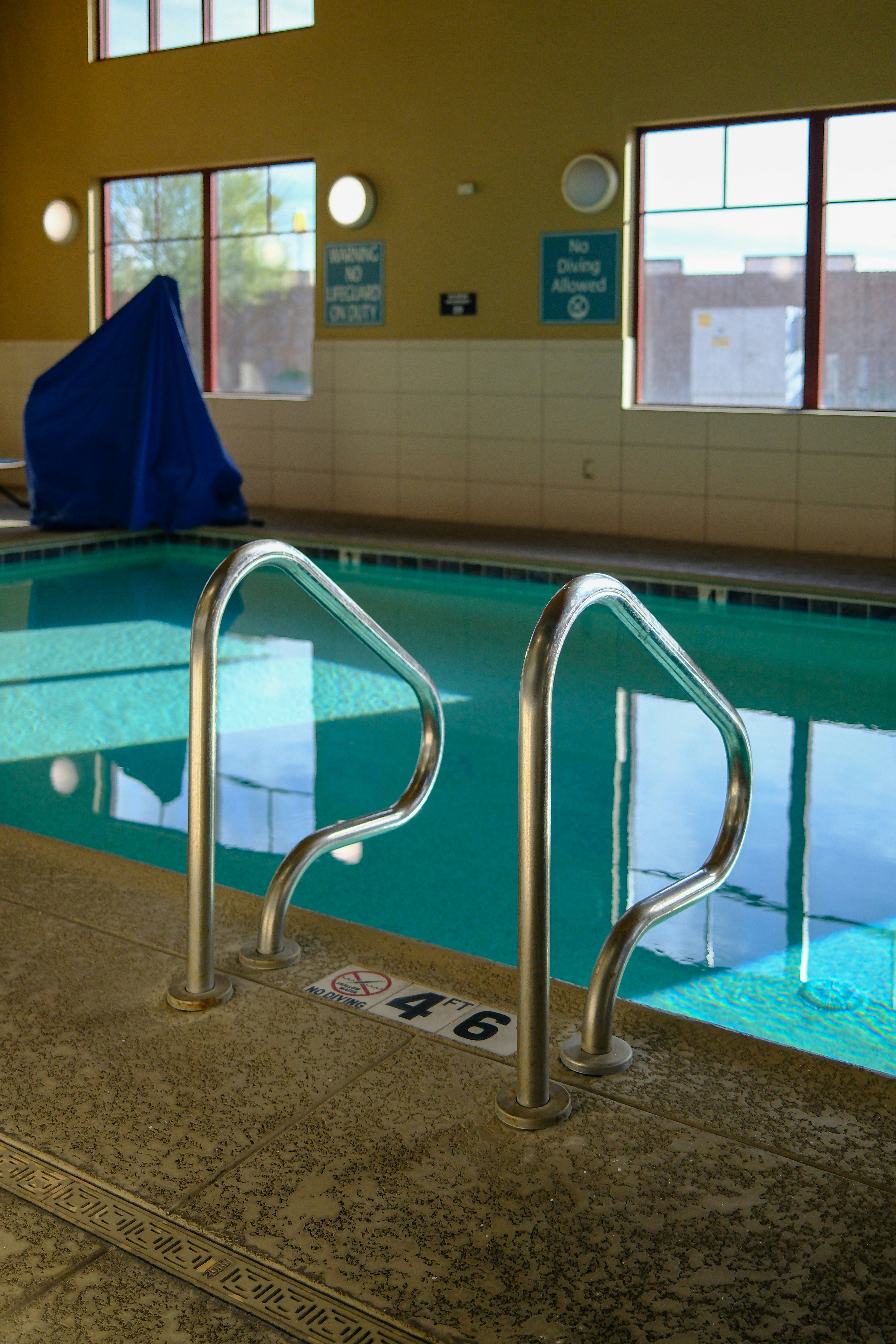 Indoor swimming pool with metal handrails and steps.