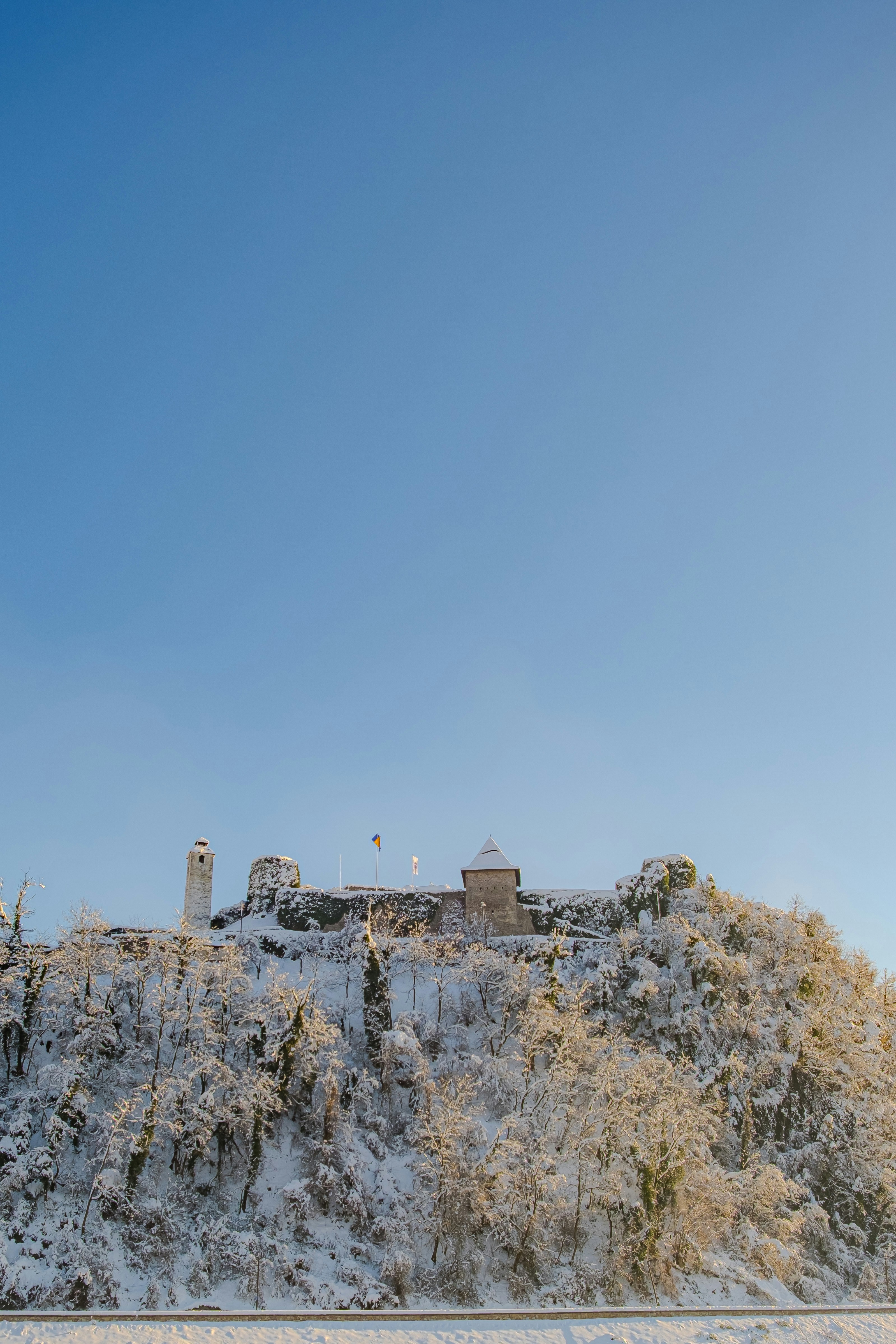 Colina coberta de neve com castelo sob céu azul claro