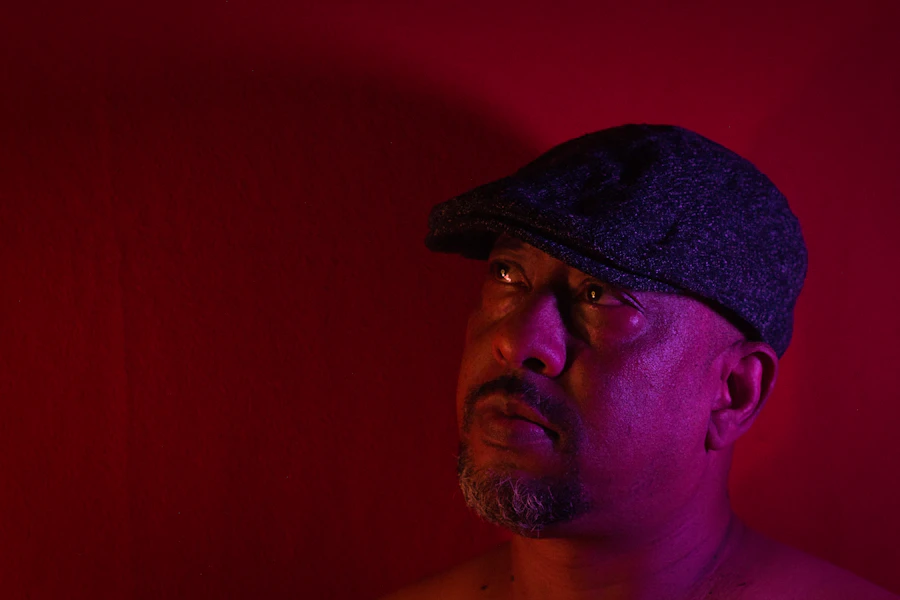 A man in a flat cap under dramatic red light