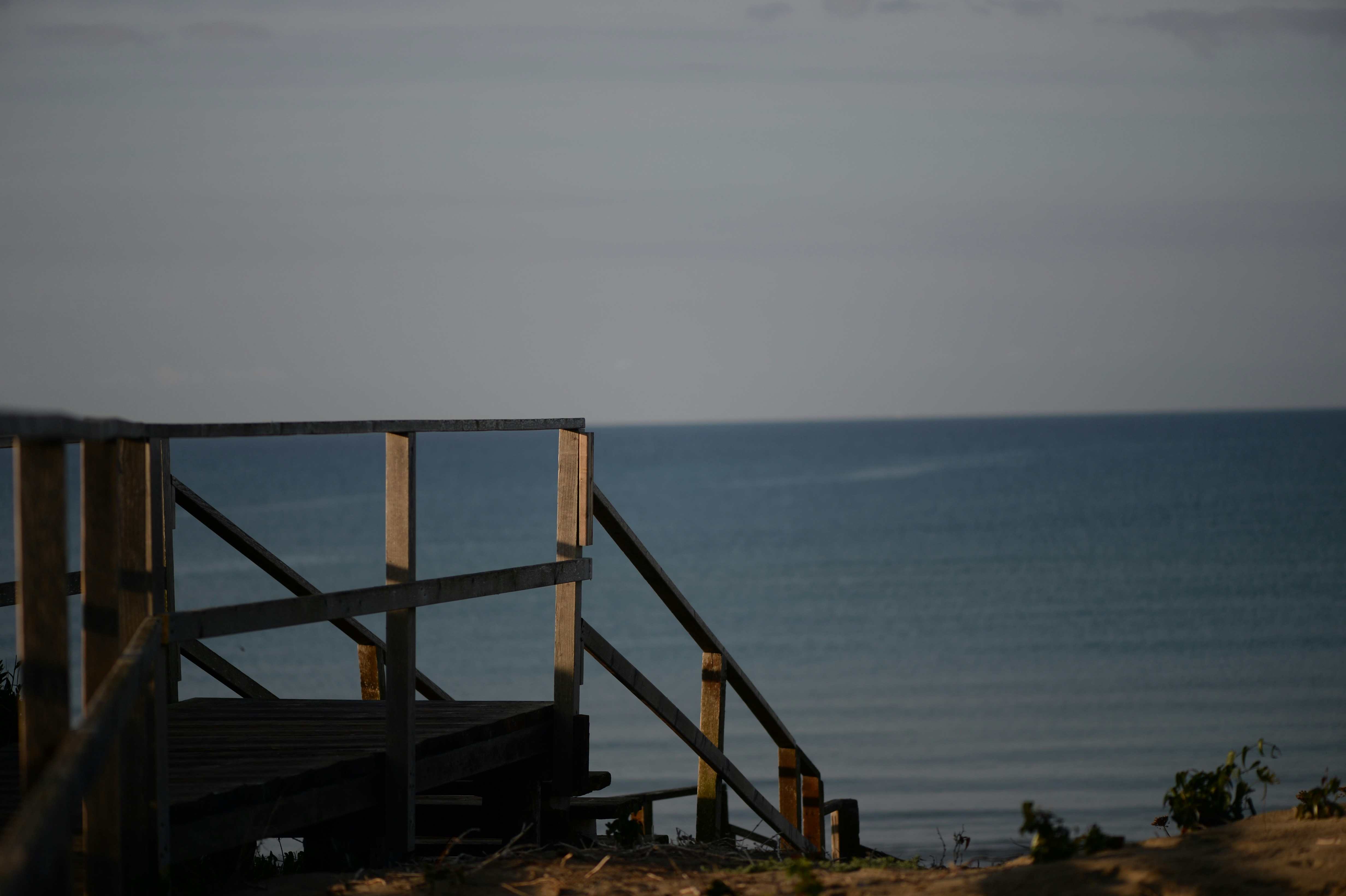Wooden stairs leading to a calm ocean view.