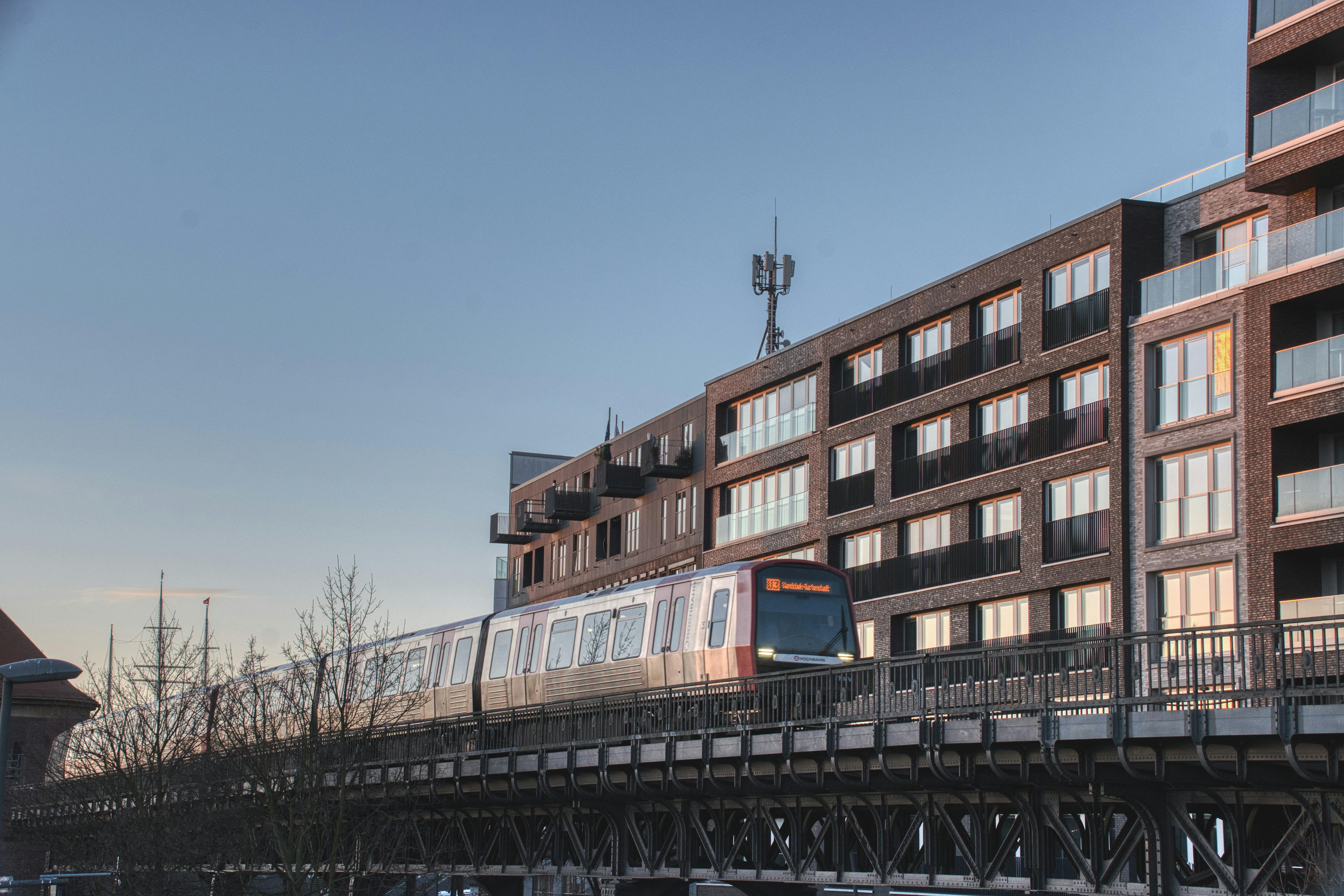 Train moving past modern apartment buildings at sunset.