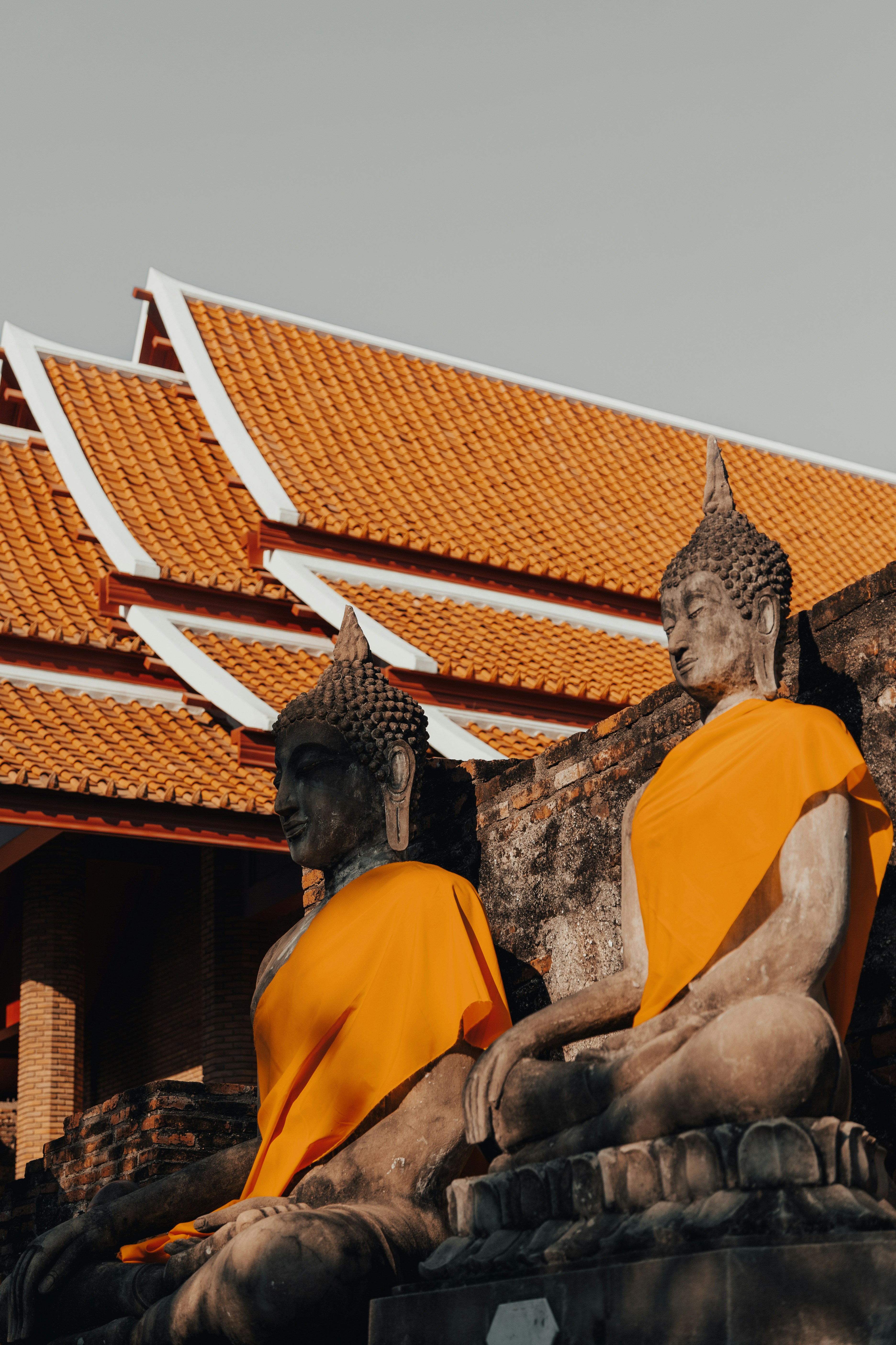 Two buddha statues draped in orange fabric.