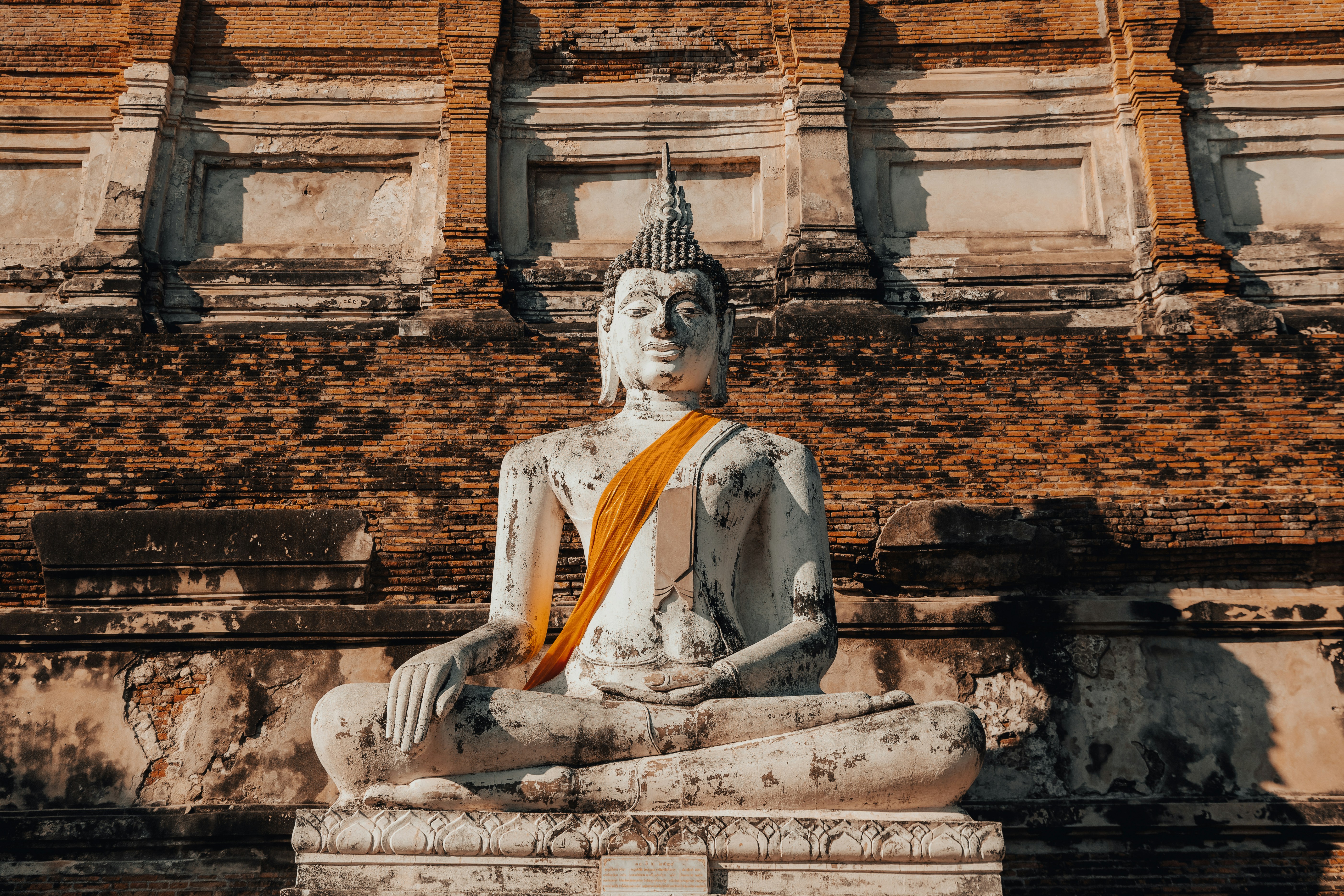 A seated buddha statue with orange cloth