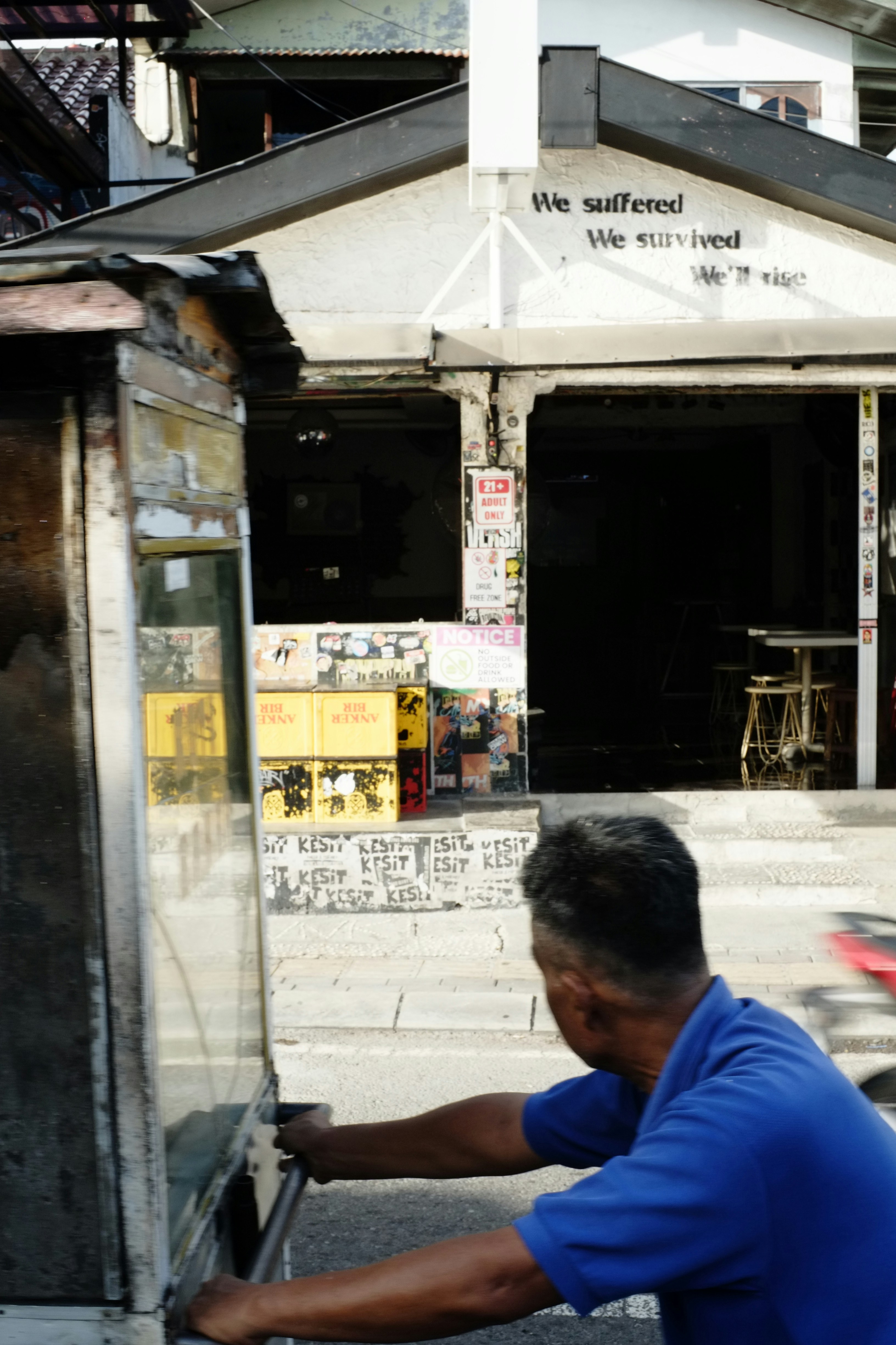 Pria mendorong gerobak di depan sebuah gedung.