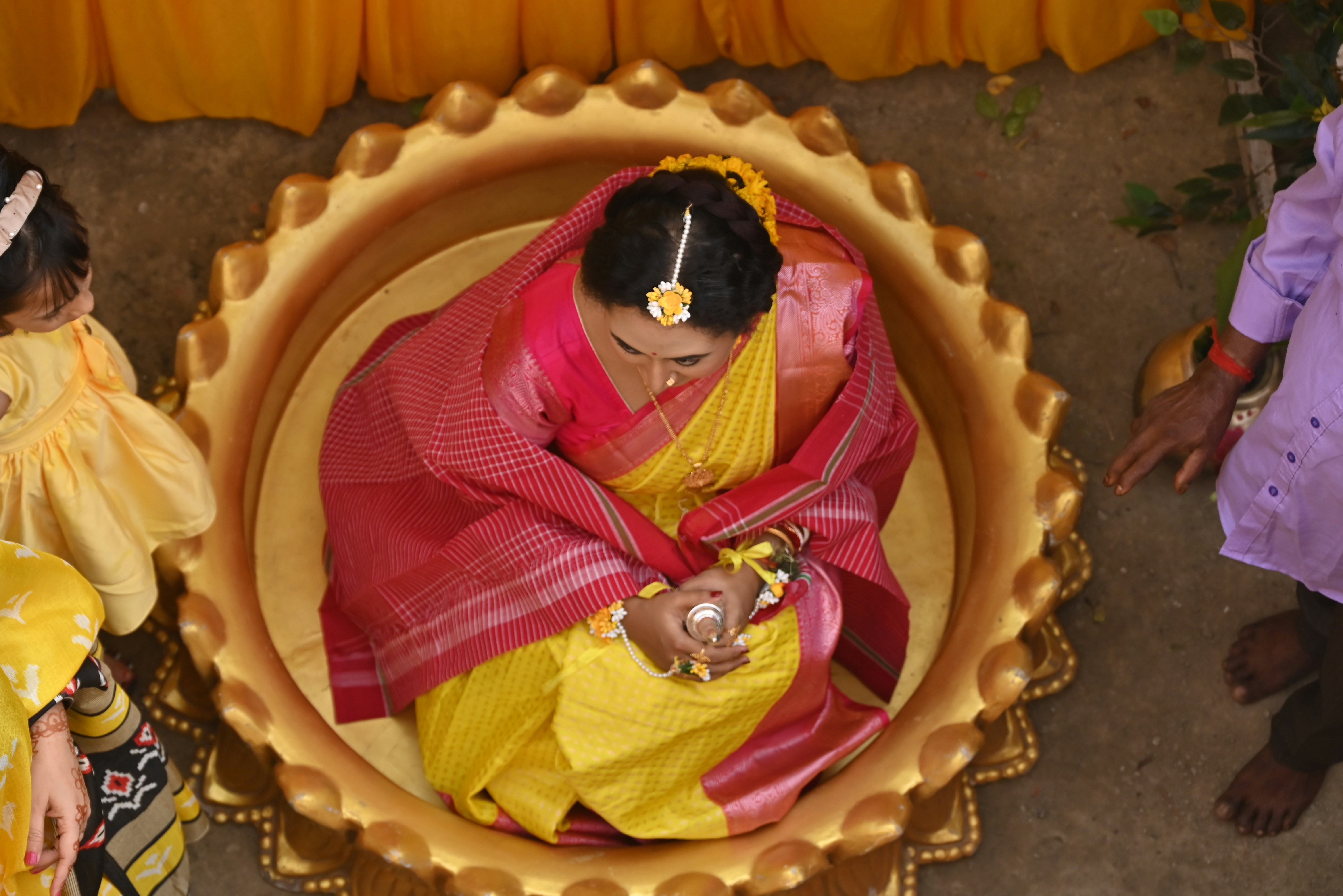 Woman in traditional indian attire sits in a golden bowl.