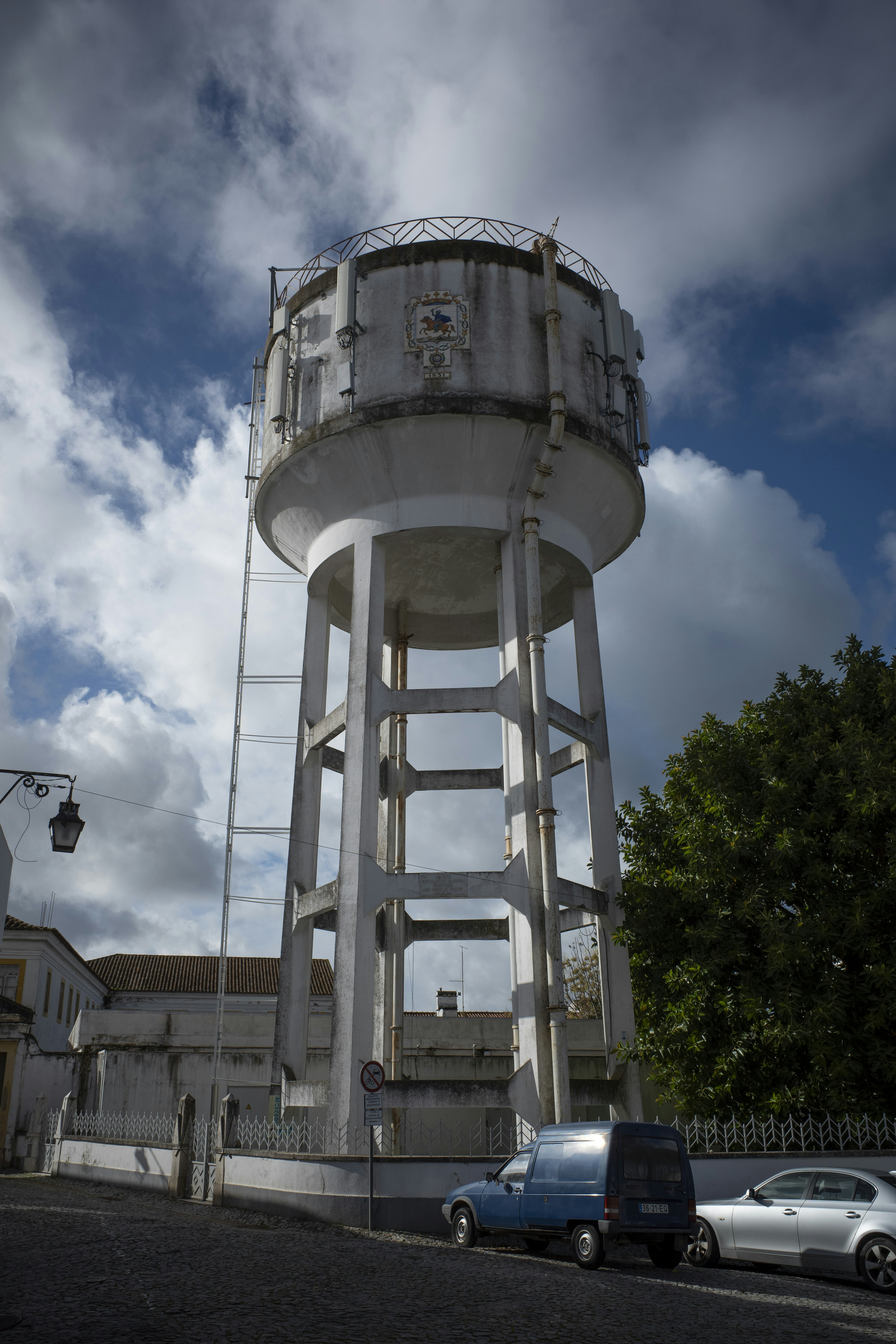 Tall concrete water tower with ladder against cloudy sky