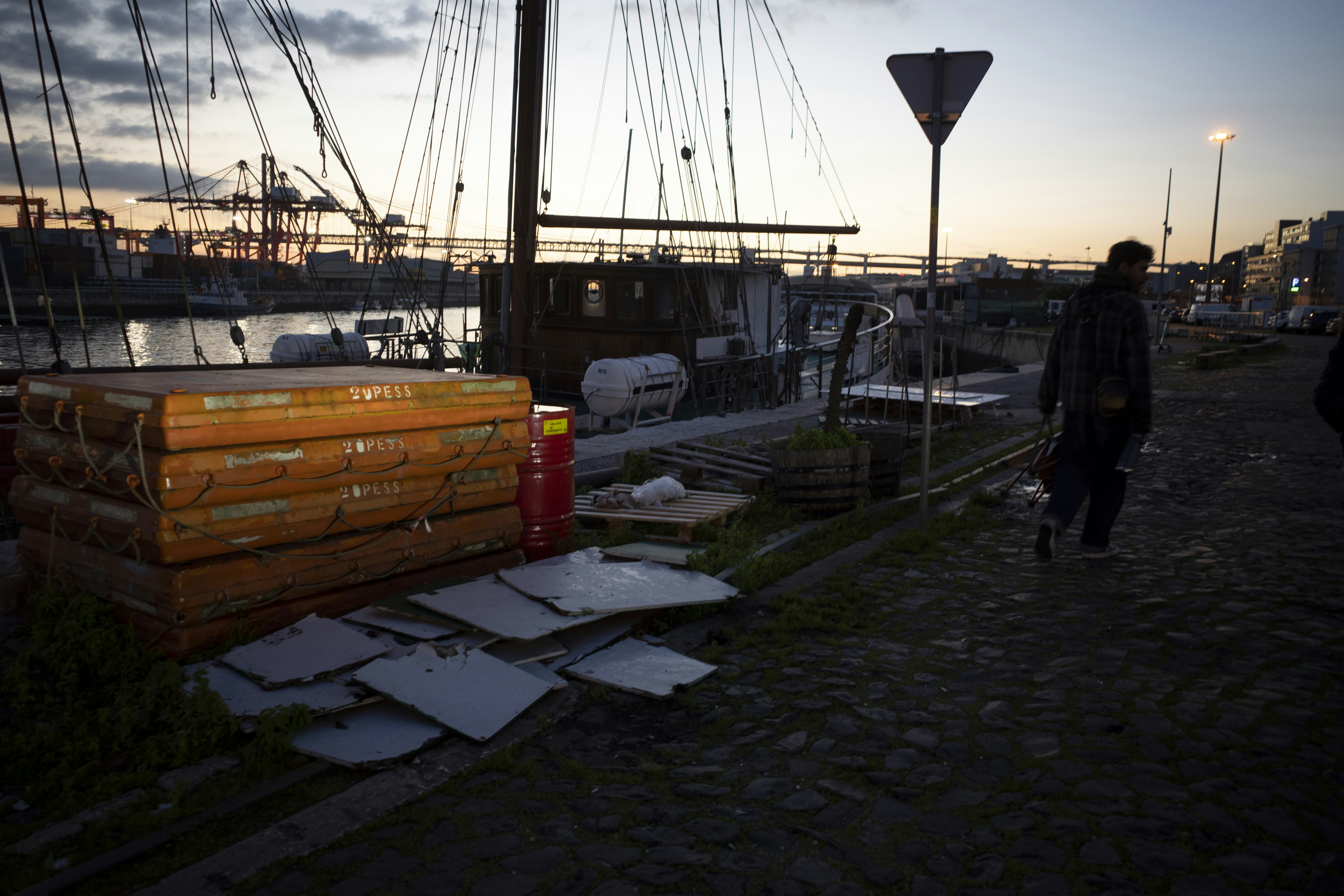 A person walks by stacked crates at dusk.