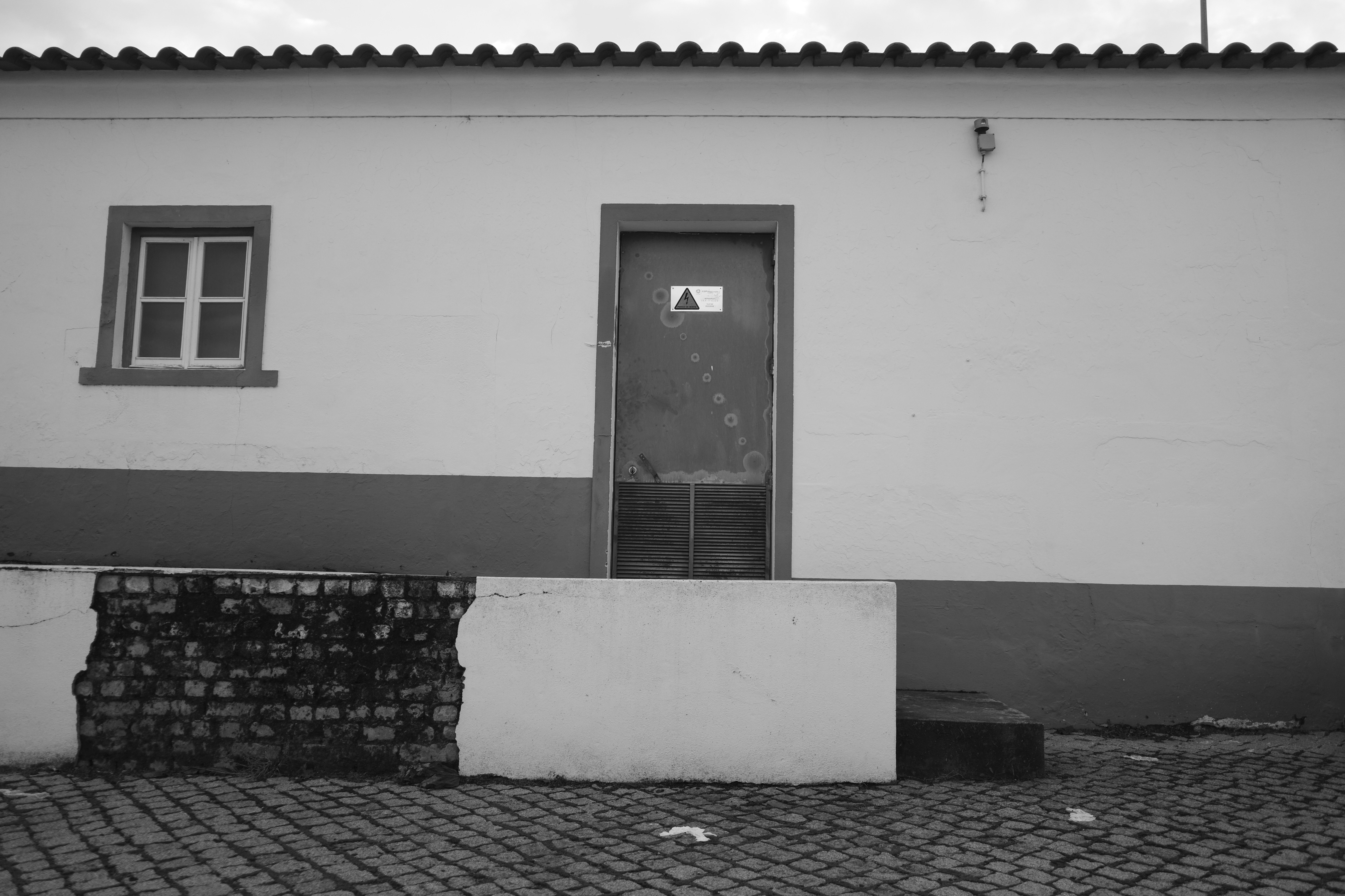 A white building with a red door and window.