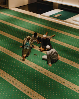 People resting on a green carpet with striped patterns.