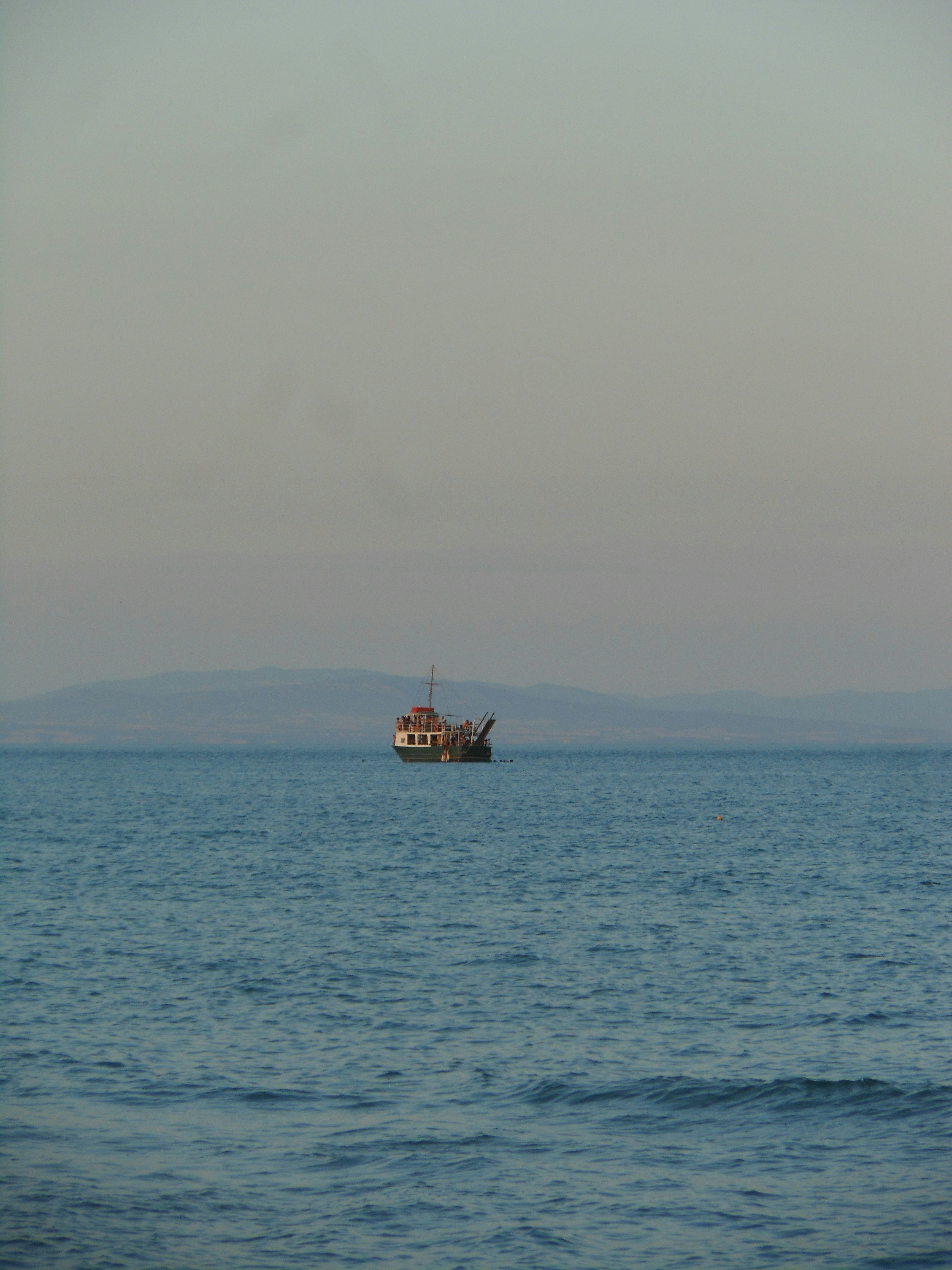 A lone boat sails on the calm sea.