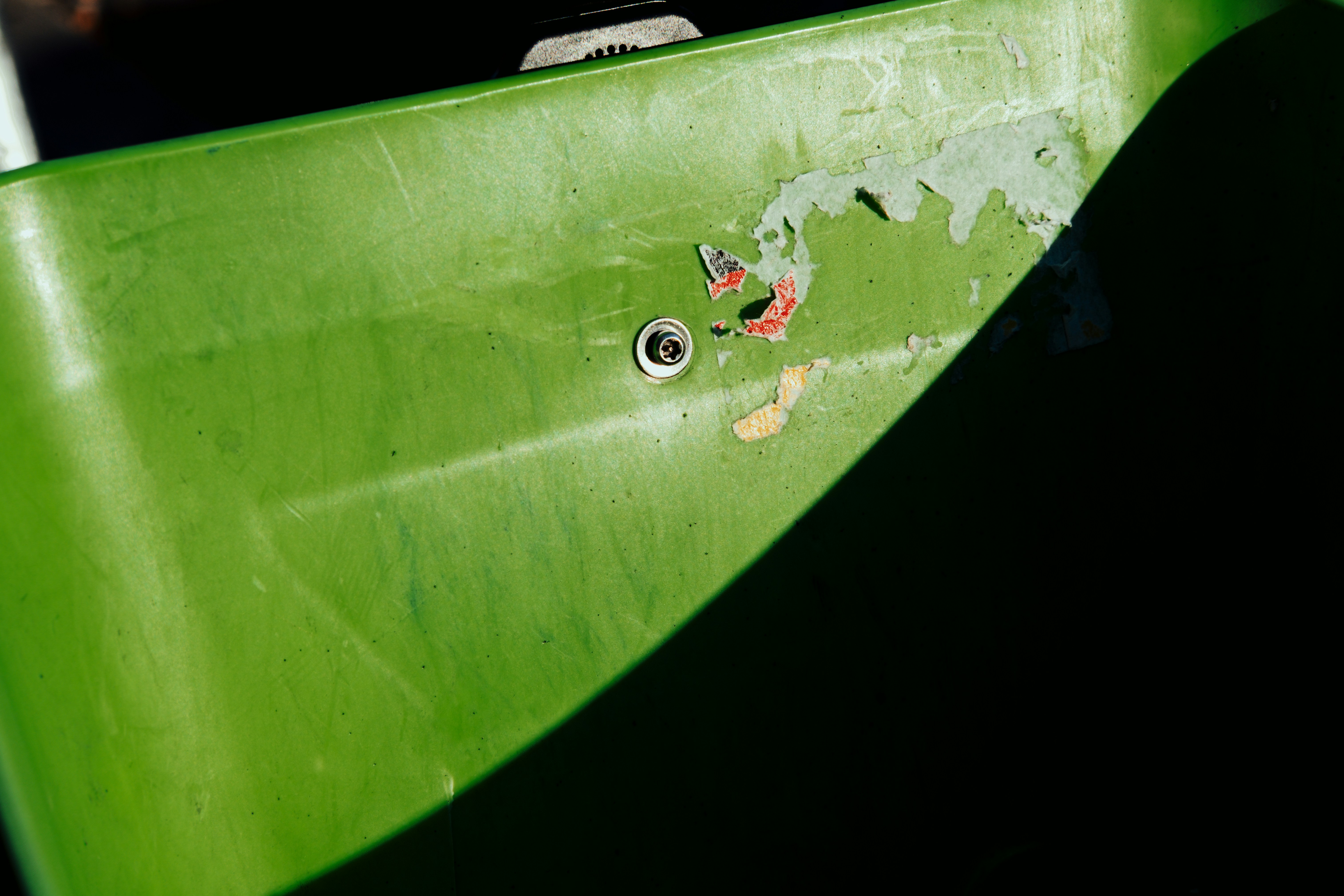 Close-up of a worn green plastic surface with a screw