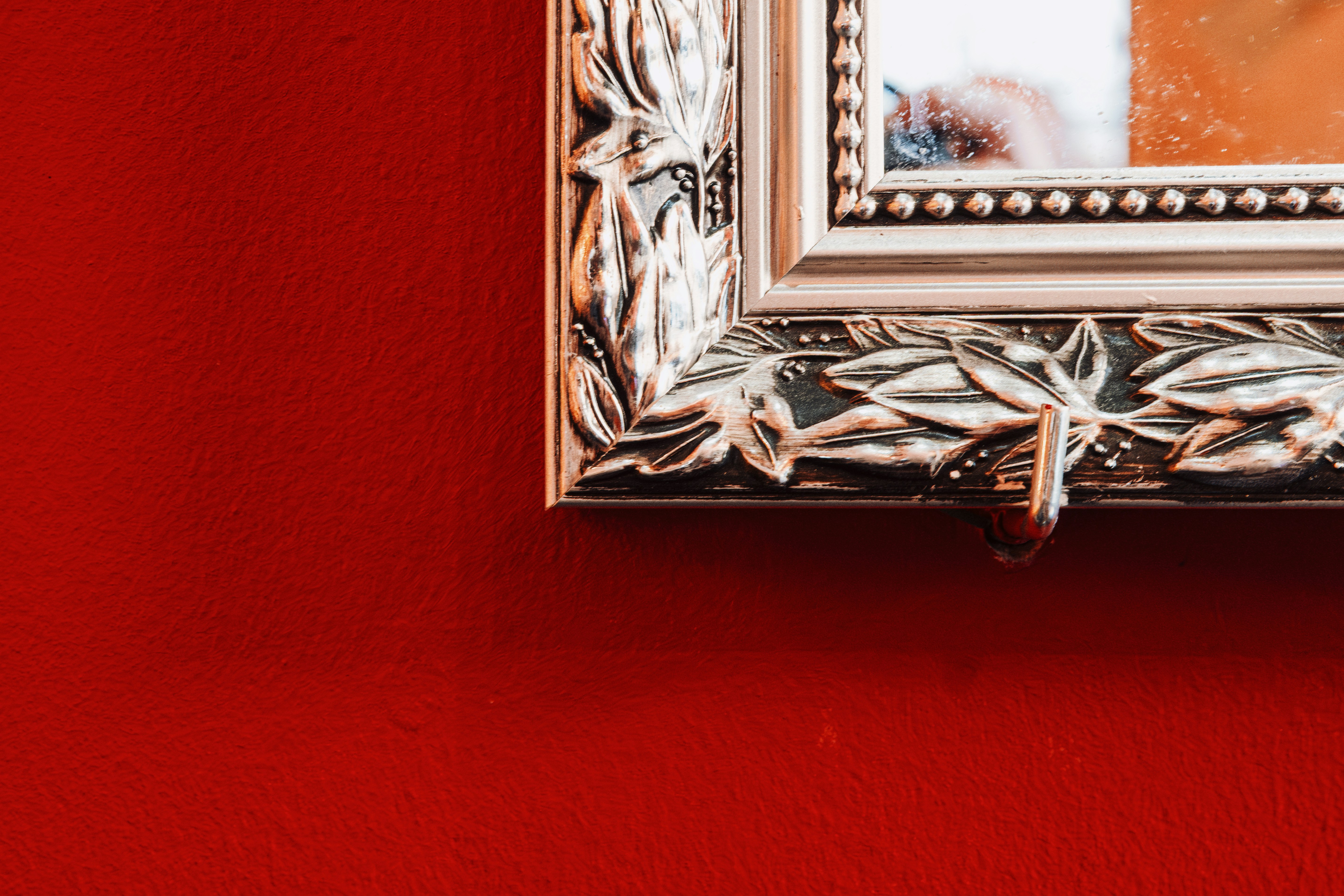 Ornate mirror frame on a red wall