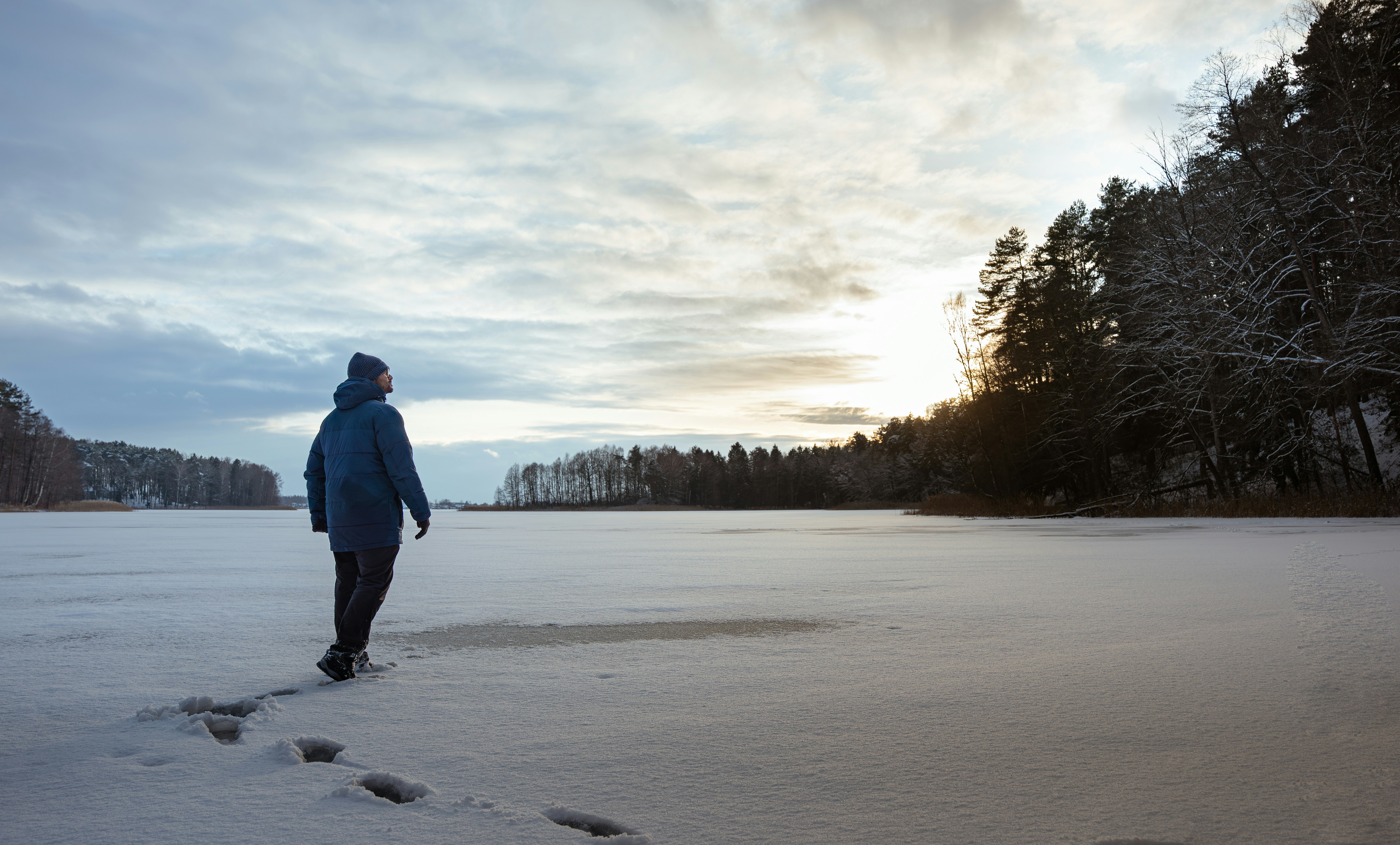 Person walking across a frozen, snow-covered lake.