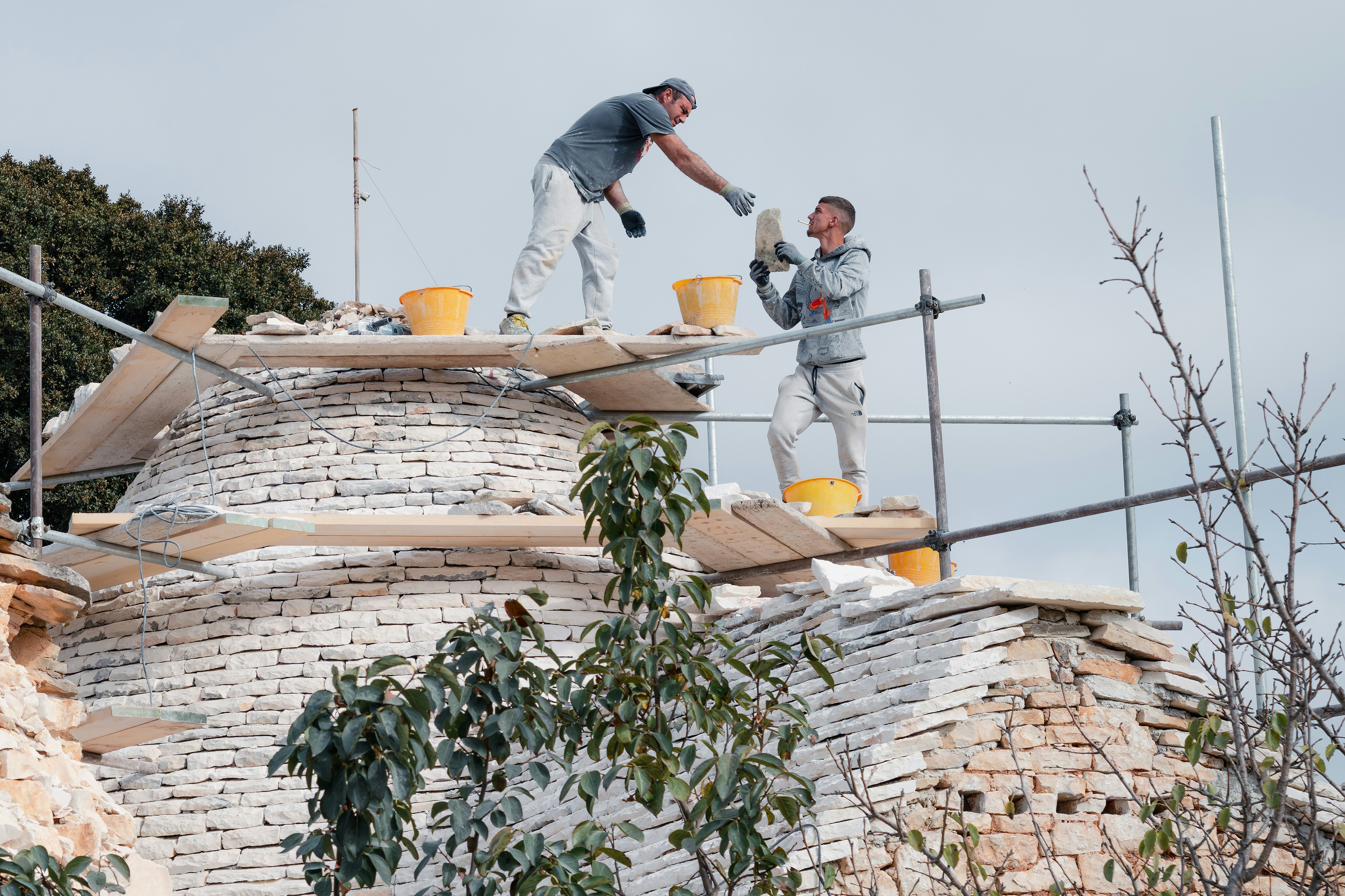 Due operai edili che riparano una struttura a cupola.