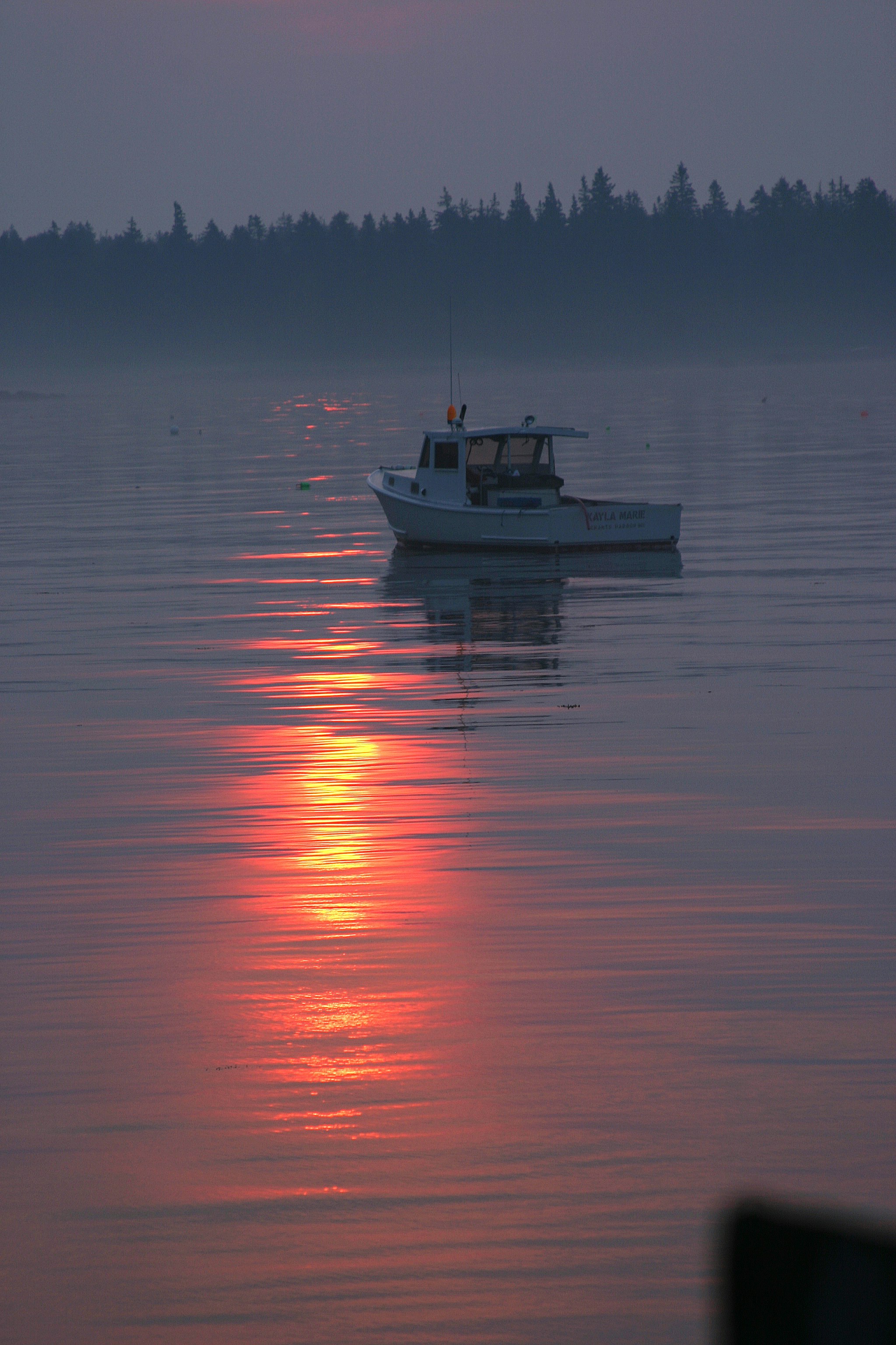 Kleines Boot auf ruhigem Wasser bei Sonnenaufgang