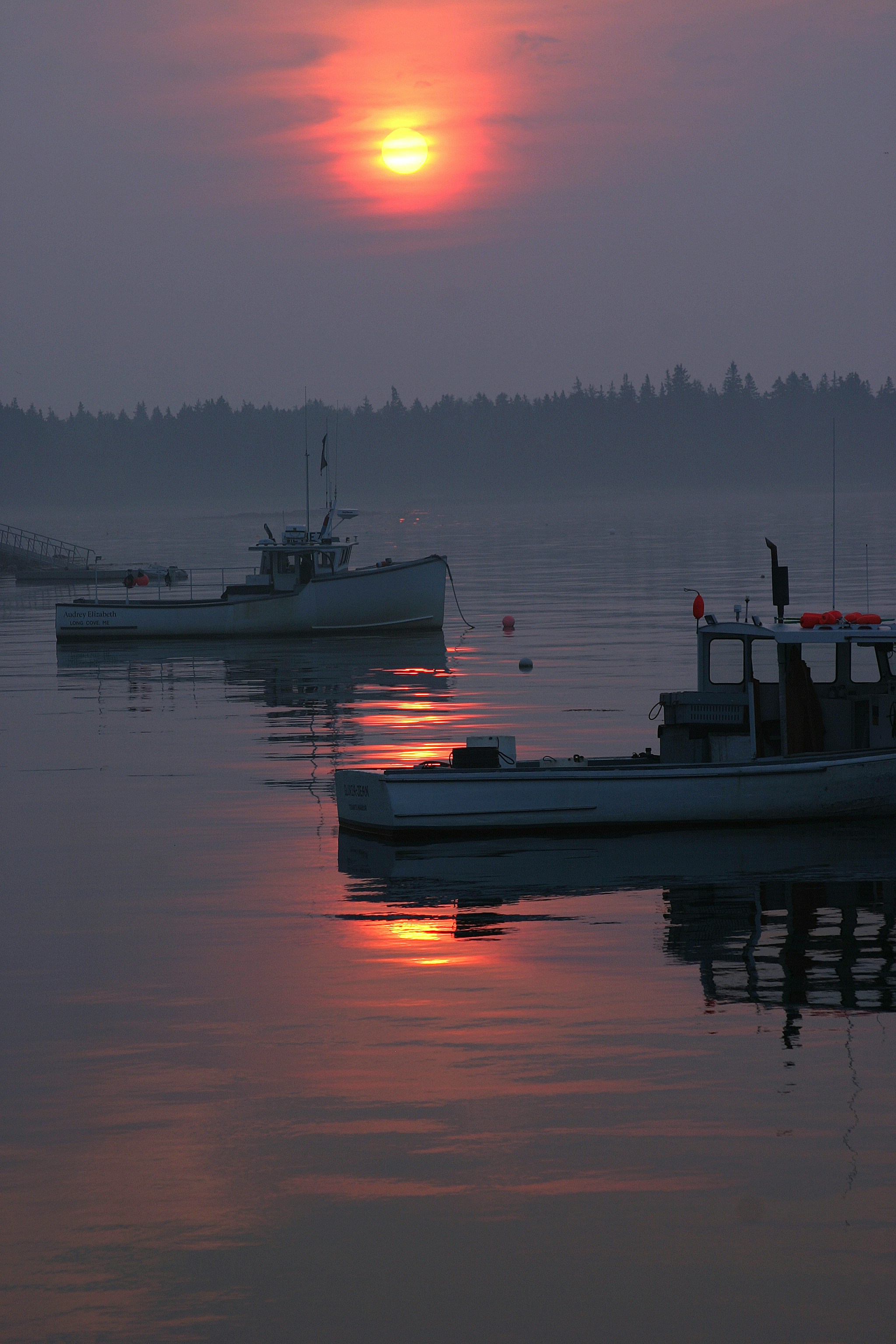 Zwei Boote treiben bei Sonnenaufgang auf ruhigem Wasser