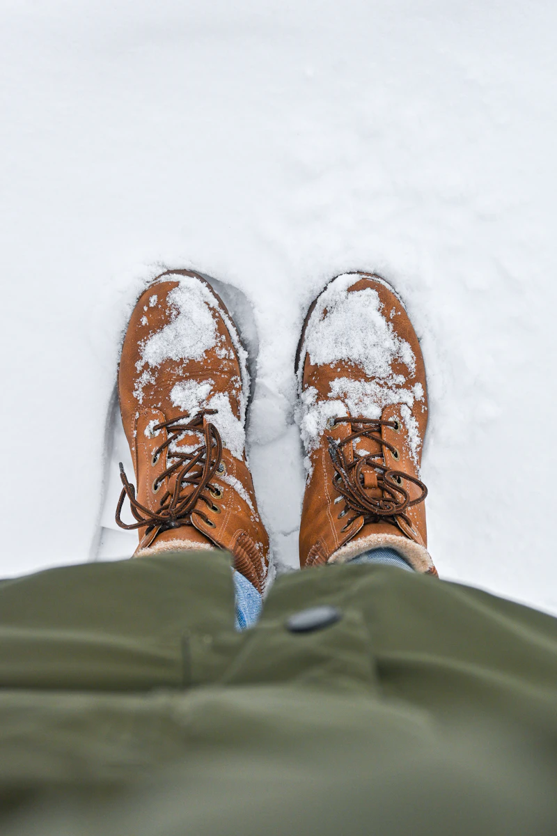 Looking down at a pair of tan winter boots dusted with snow