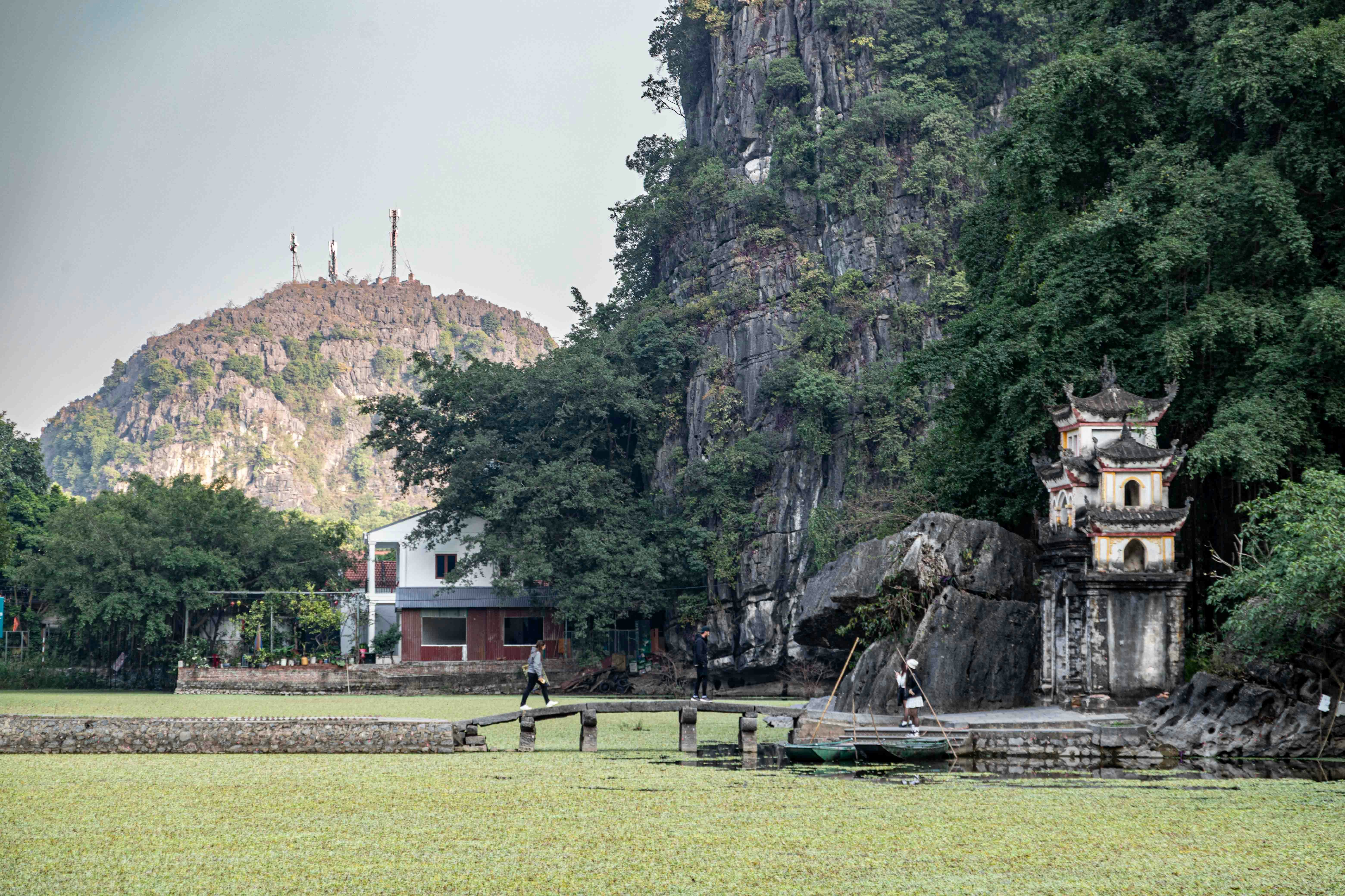 A pagoda structure stands near a rocky cliff face.