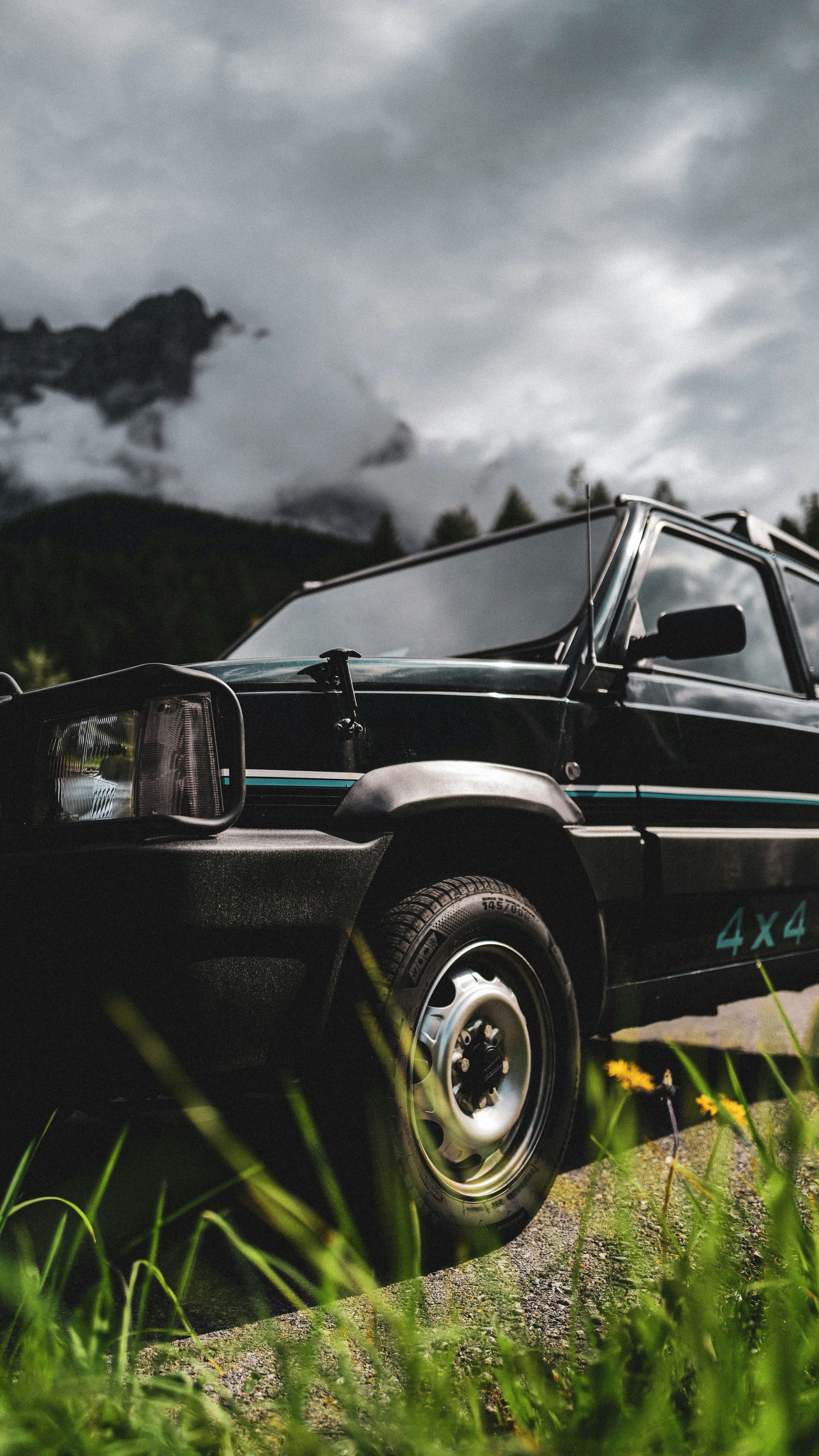 Veicolo fuoristrada scuro parcheggiato vicino a montagne erbose.