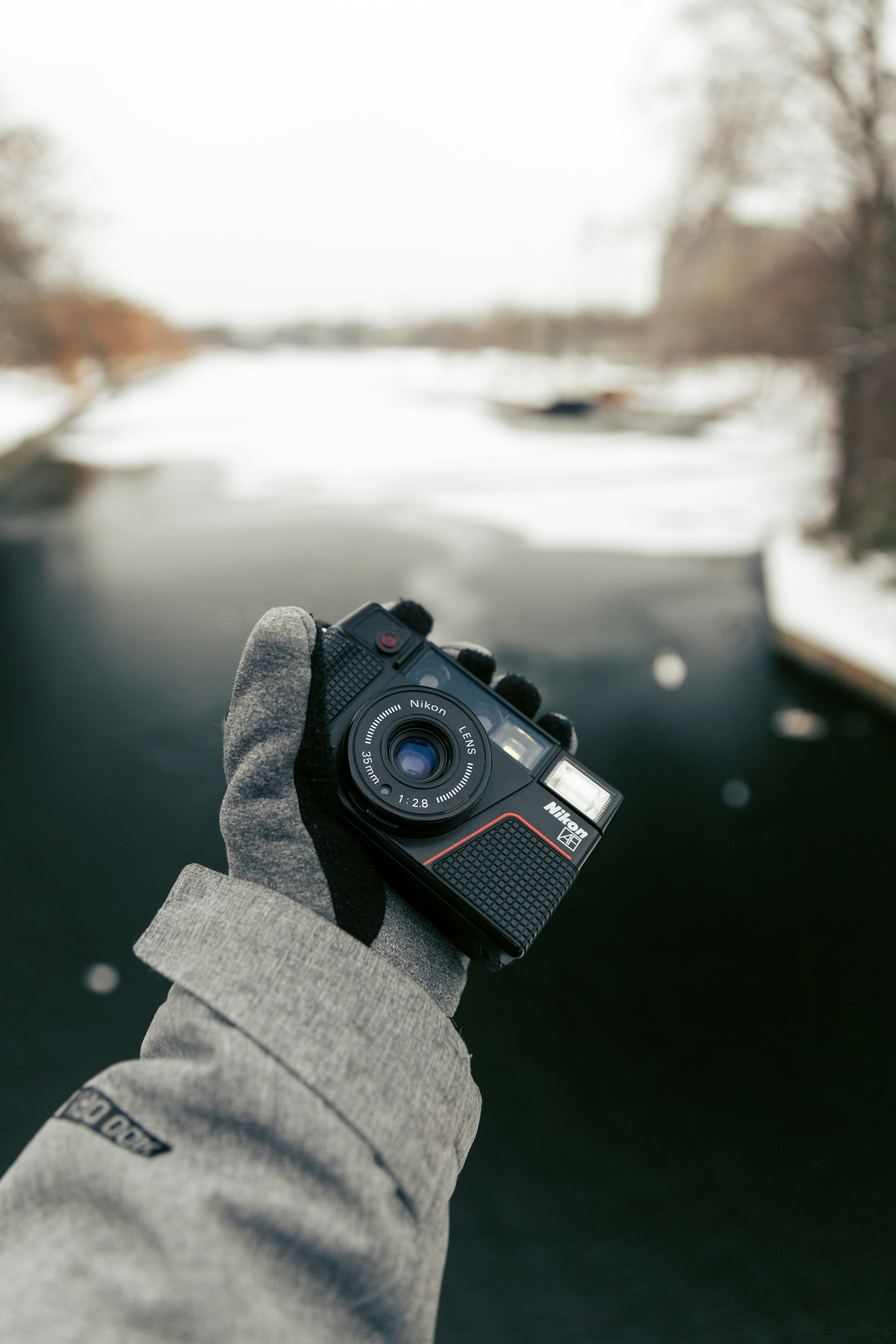 Hand holding vintage camera over frozen canal