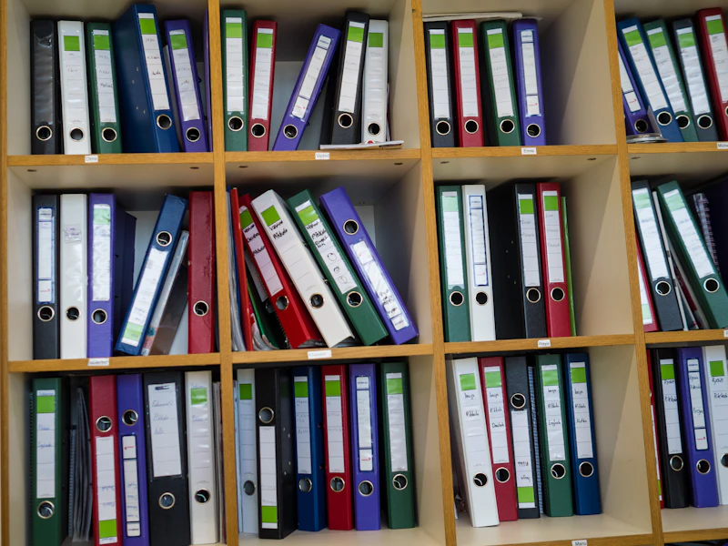 Regale gefüllt mit bunten Ordnern und Aktenmappen als Symbol für Organisation