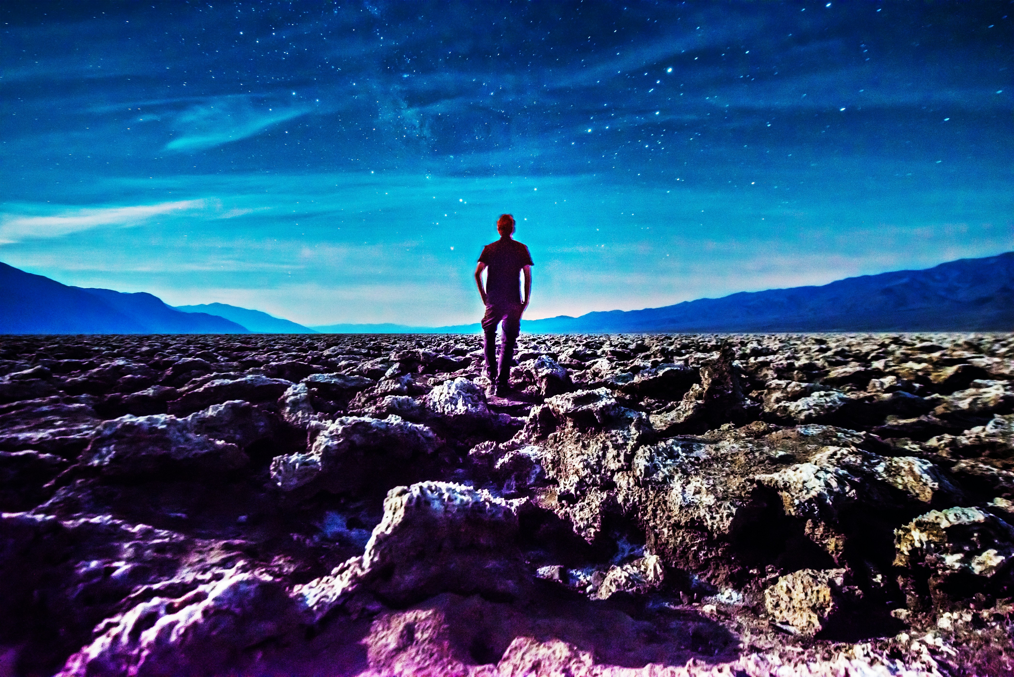 Lone figure on desert landscape under night sky