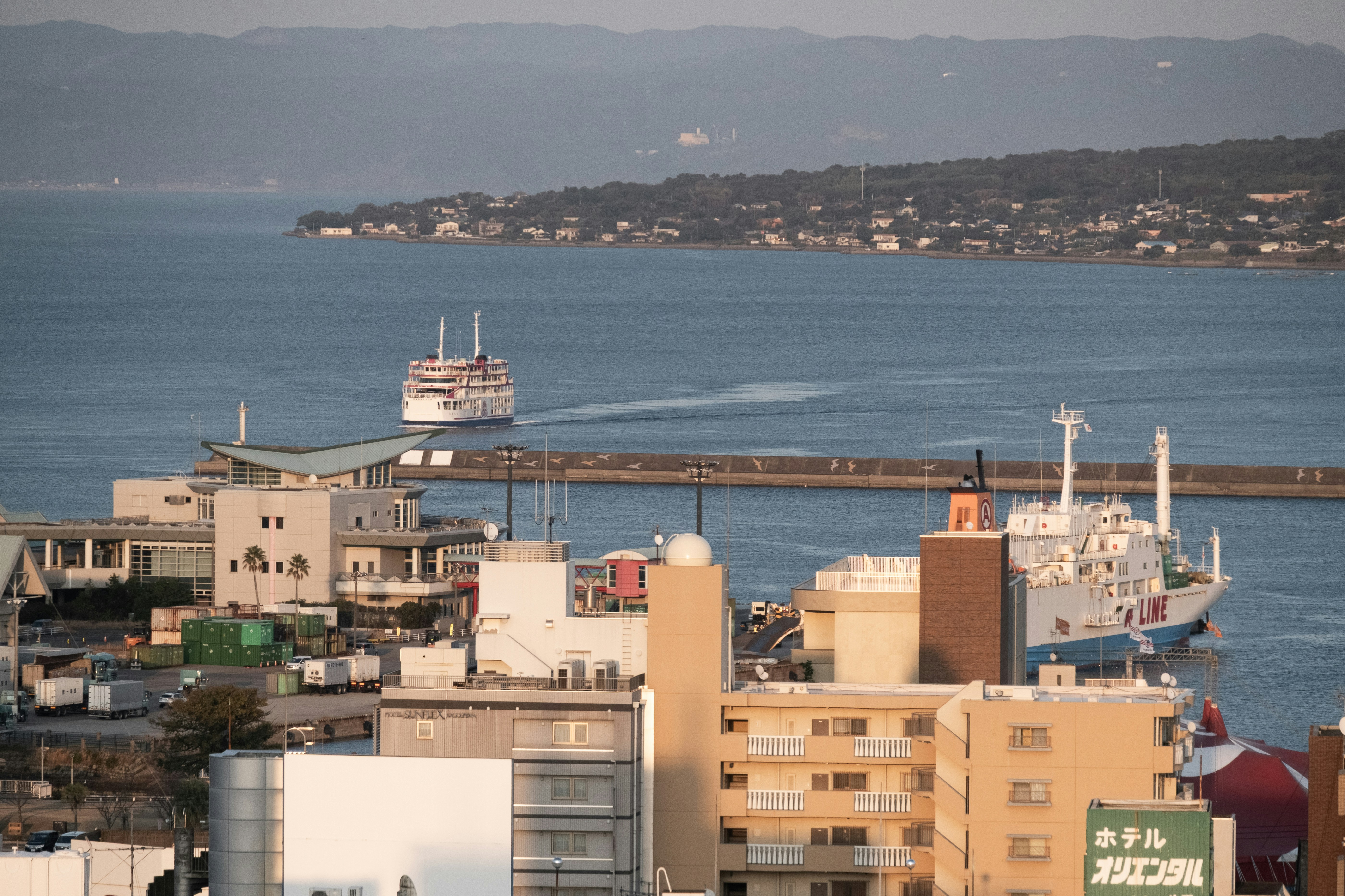 Two ships sail in a harbor near a coastal town.