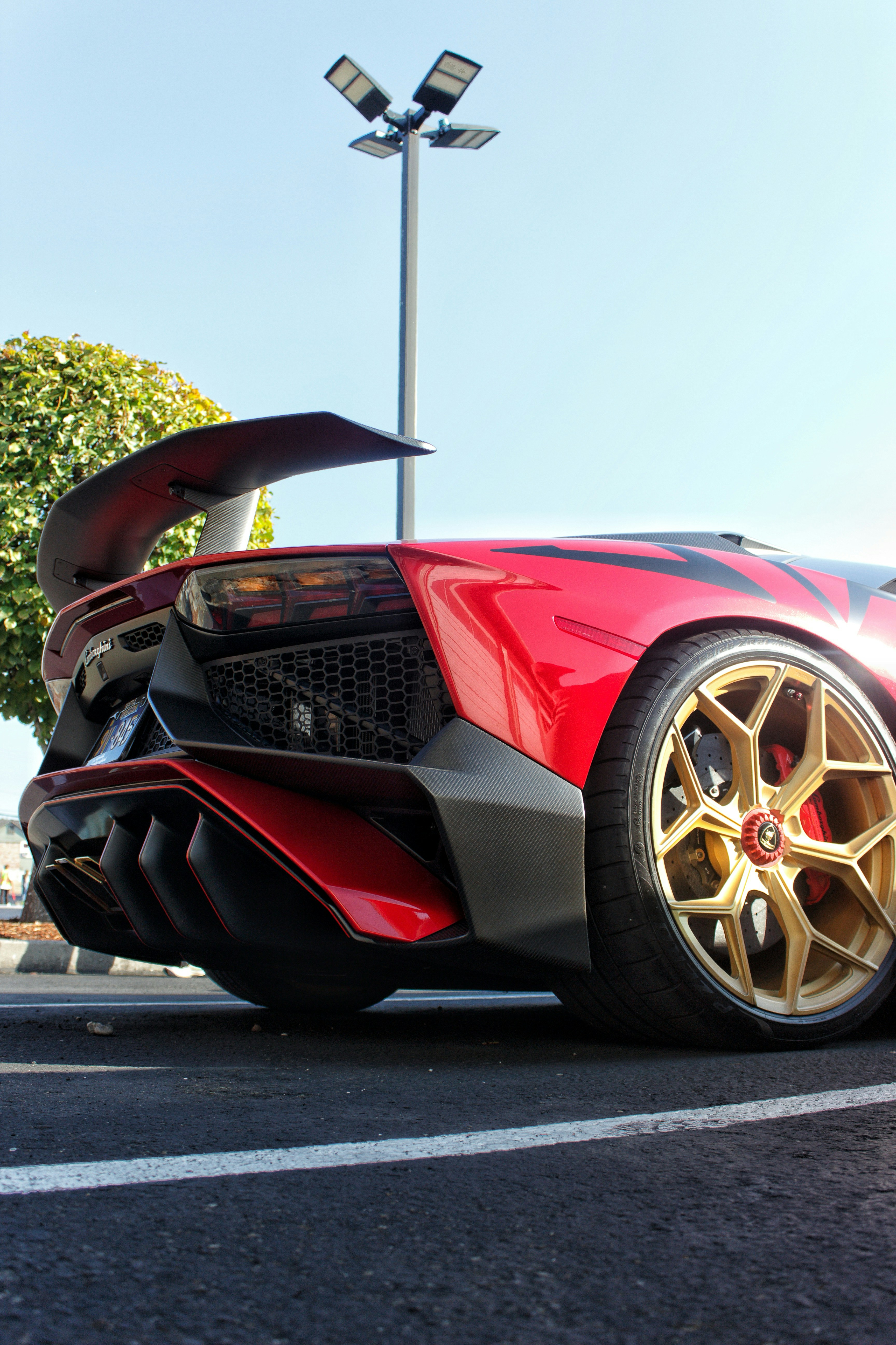 Auto sportiva rossa con ruote dorate parcheggiate all'esterno