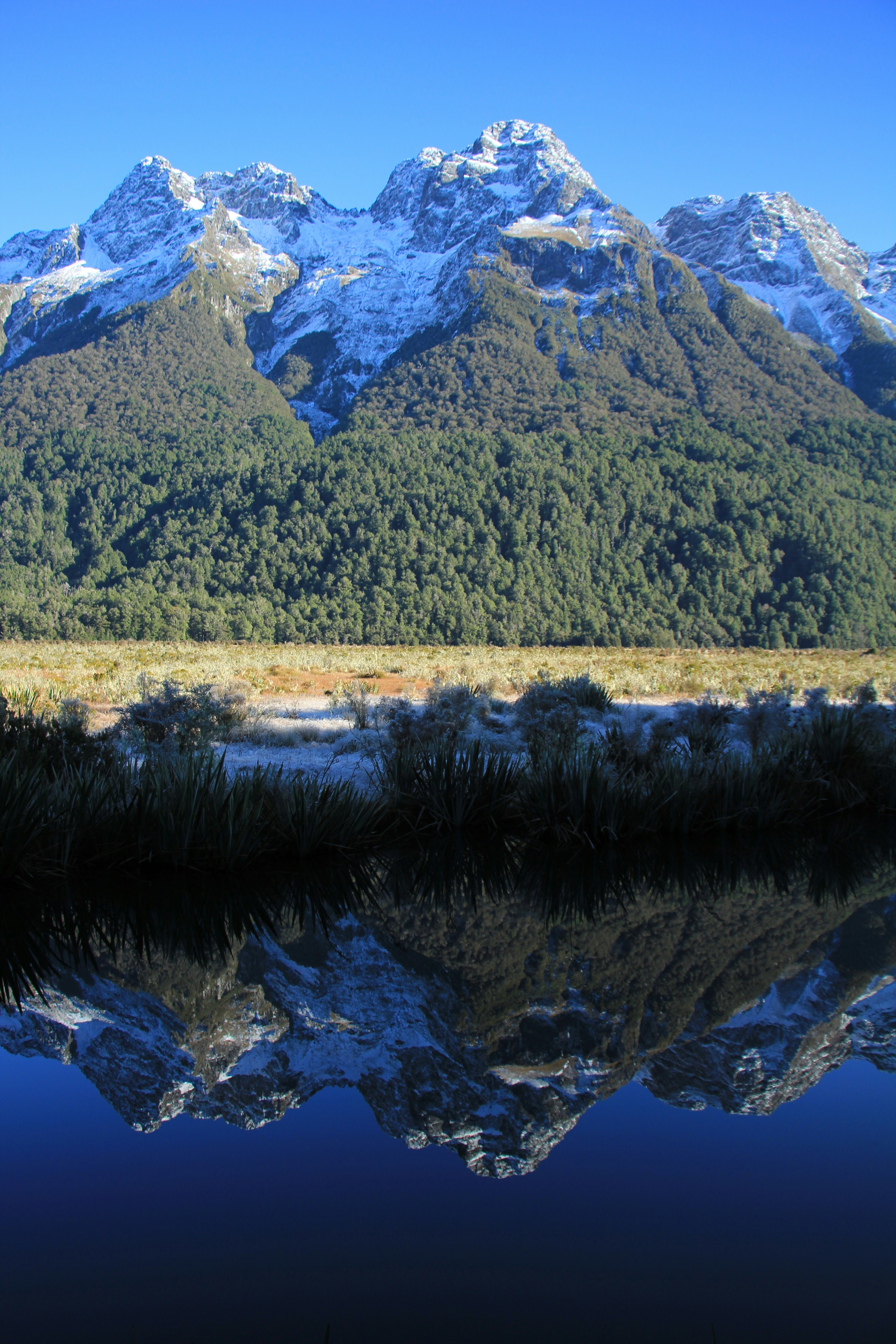 Snow-capped mountains reflected in a calm lake.