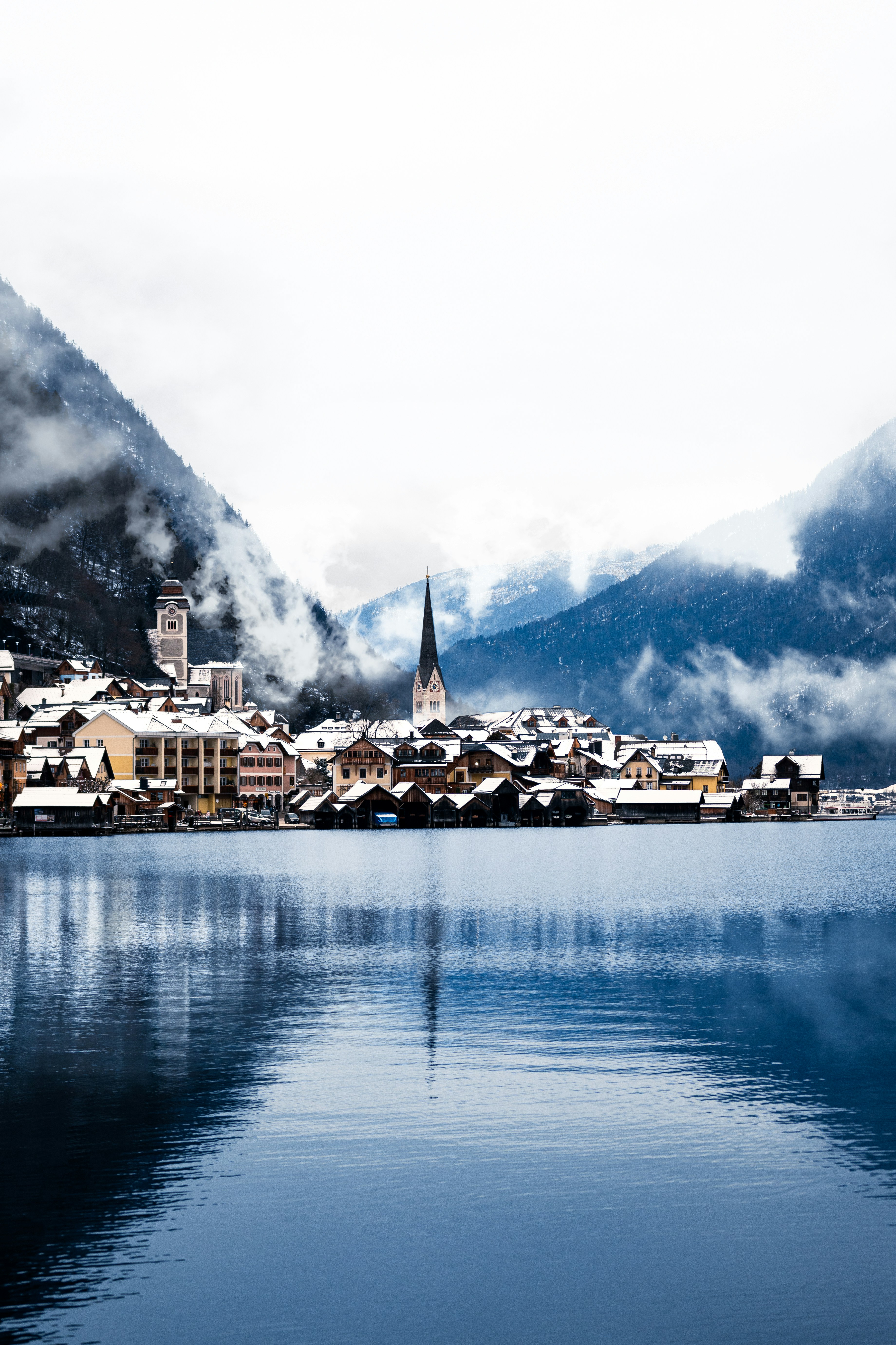 Pueblo nevado enclavado junto a un lago tranquilo y montañas.