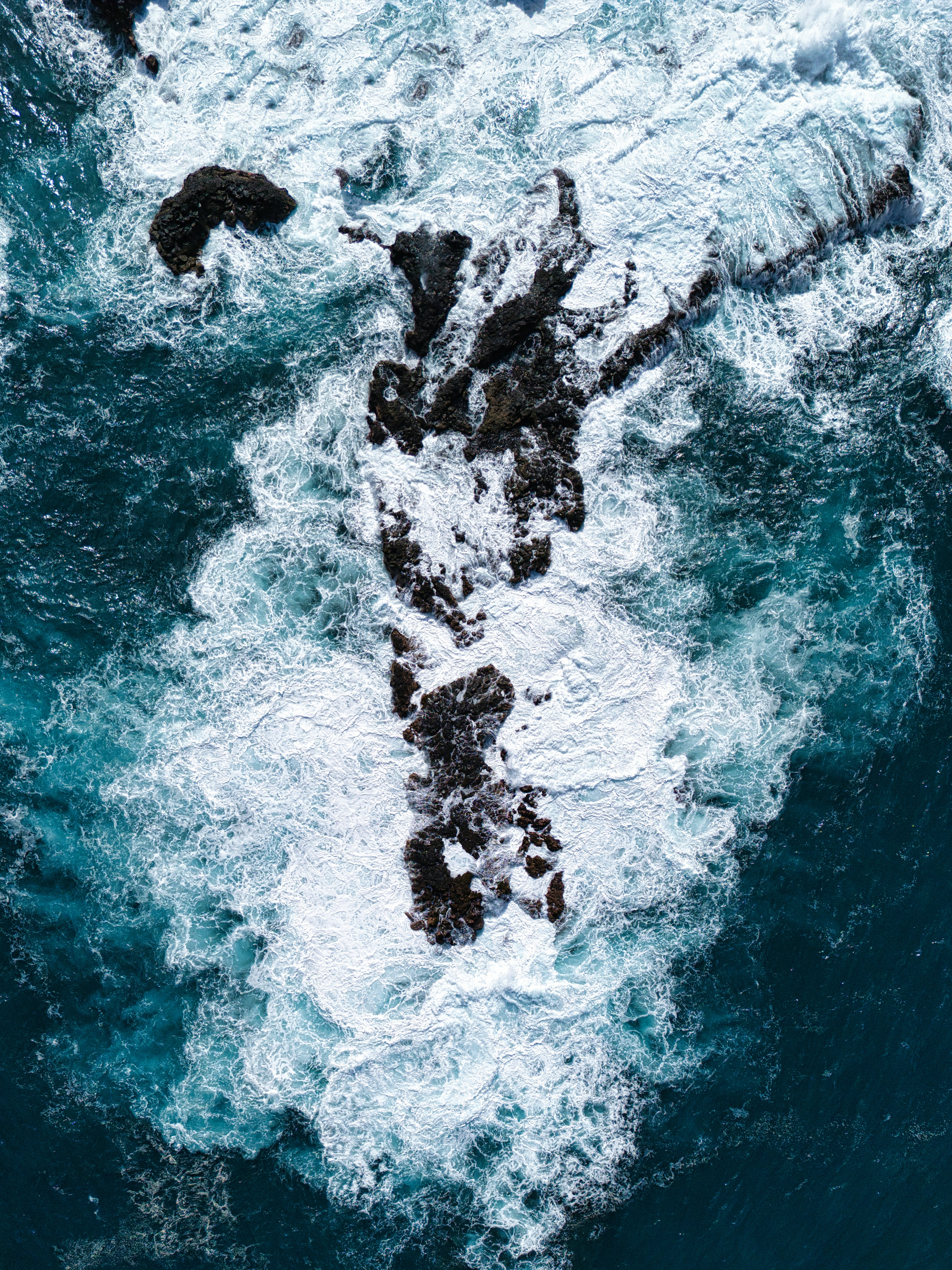 Waves crashing against dark rocks in the ocean.