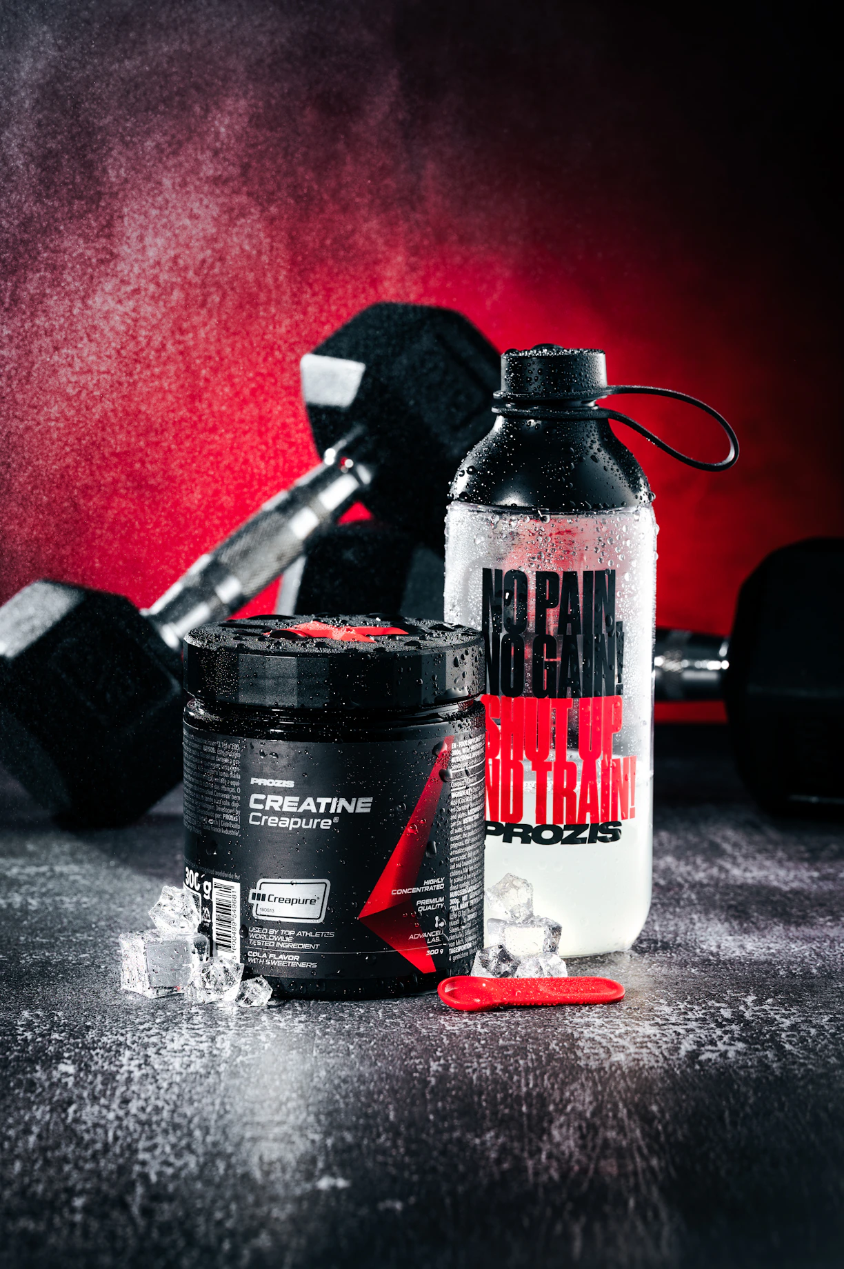 Creatine supplement, water bottle, and dumbbells on wet surface.