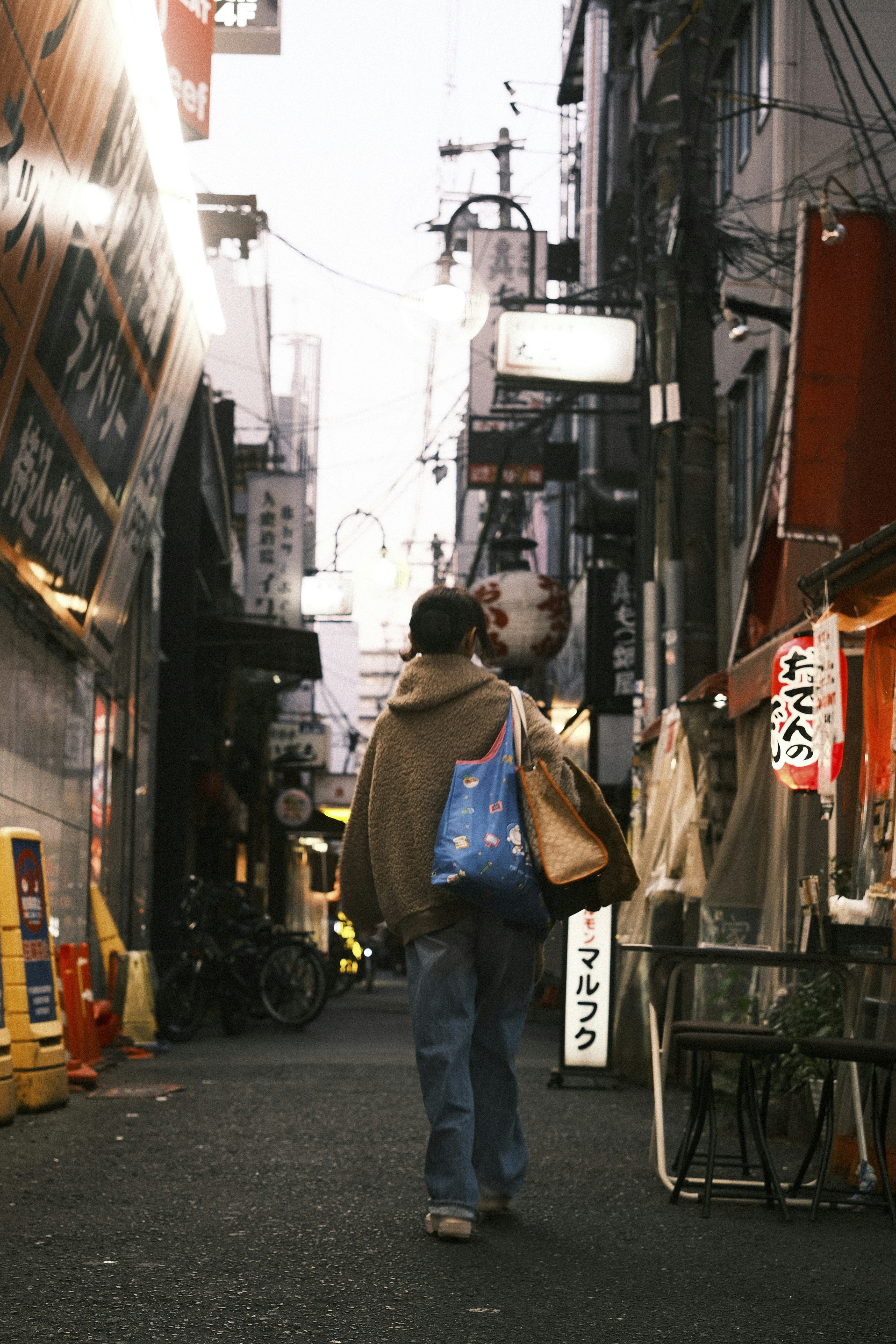 Person walks down a narrow, dimly lit street.