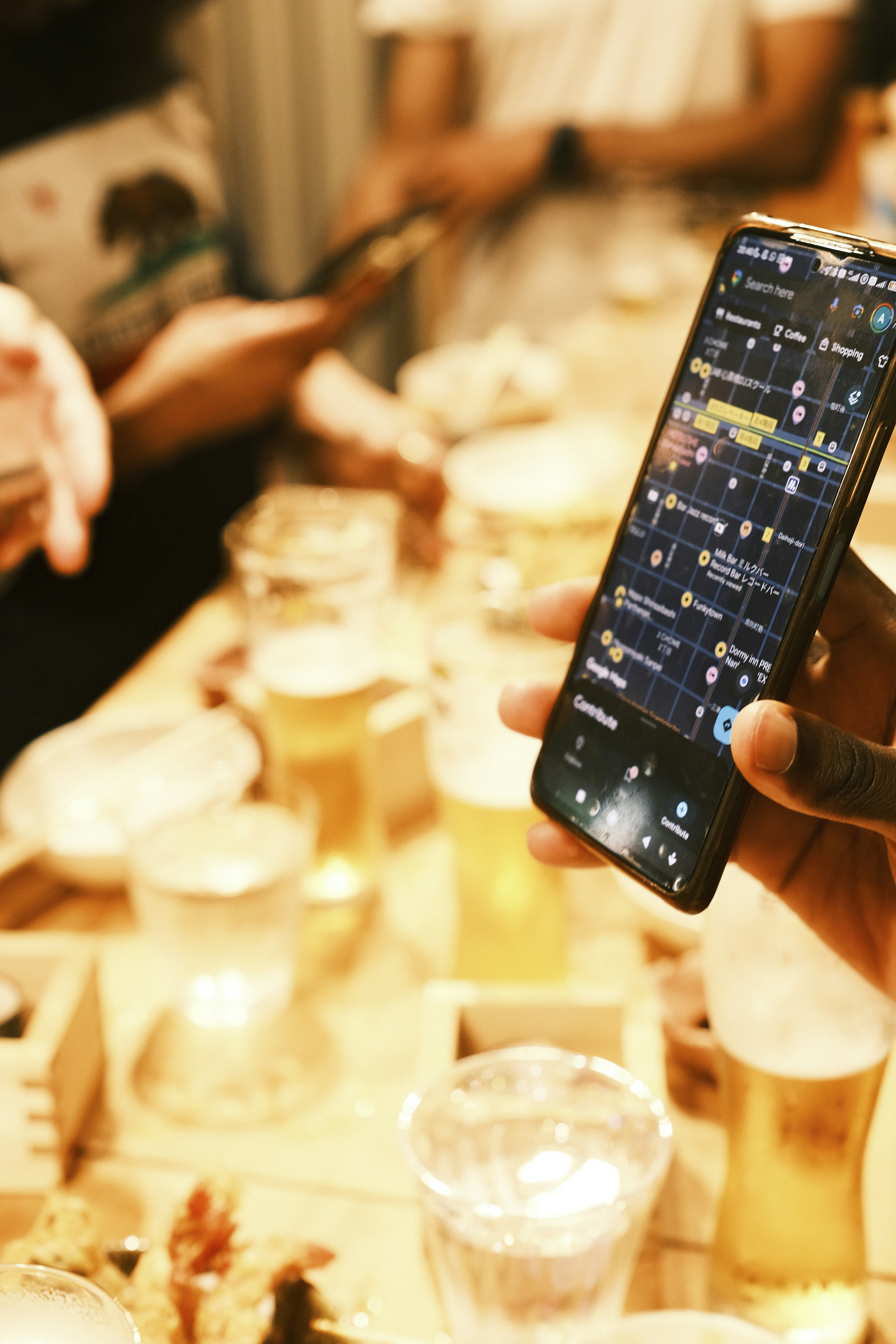 Person holding smartphone with map app over drinks