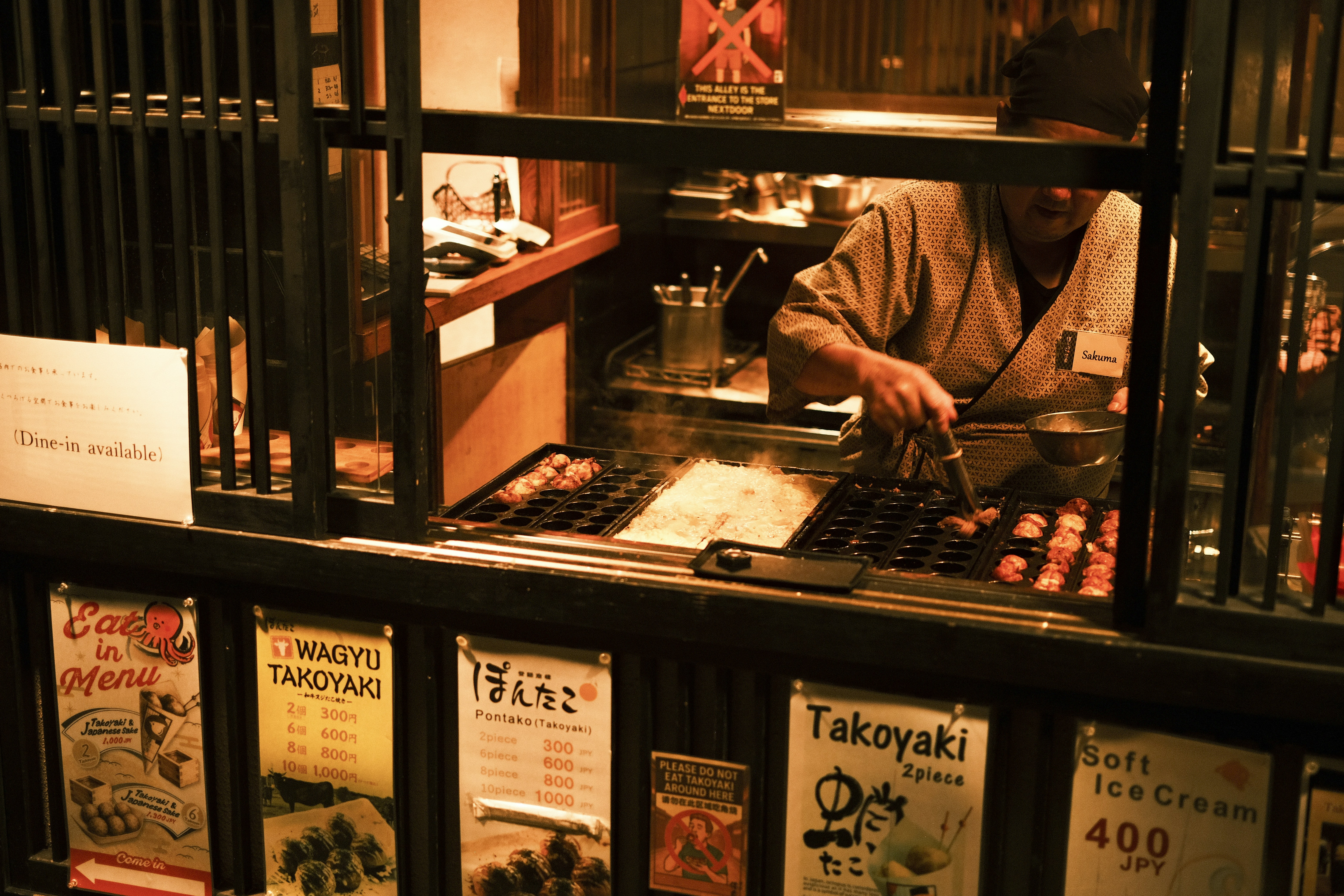 Chef preparing takoyaki at a street food stall.