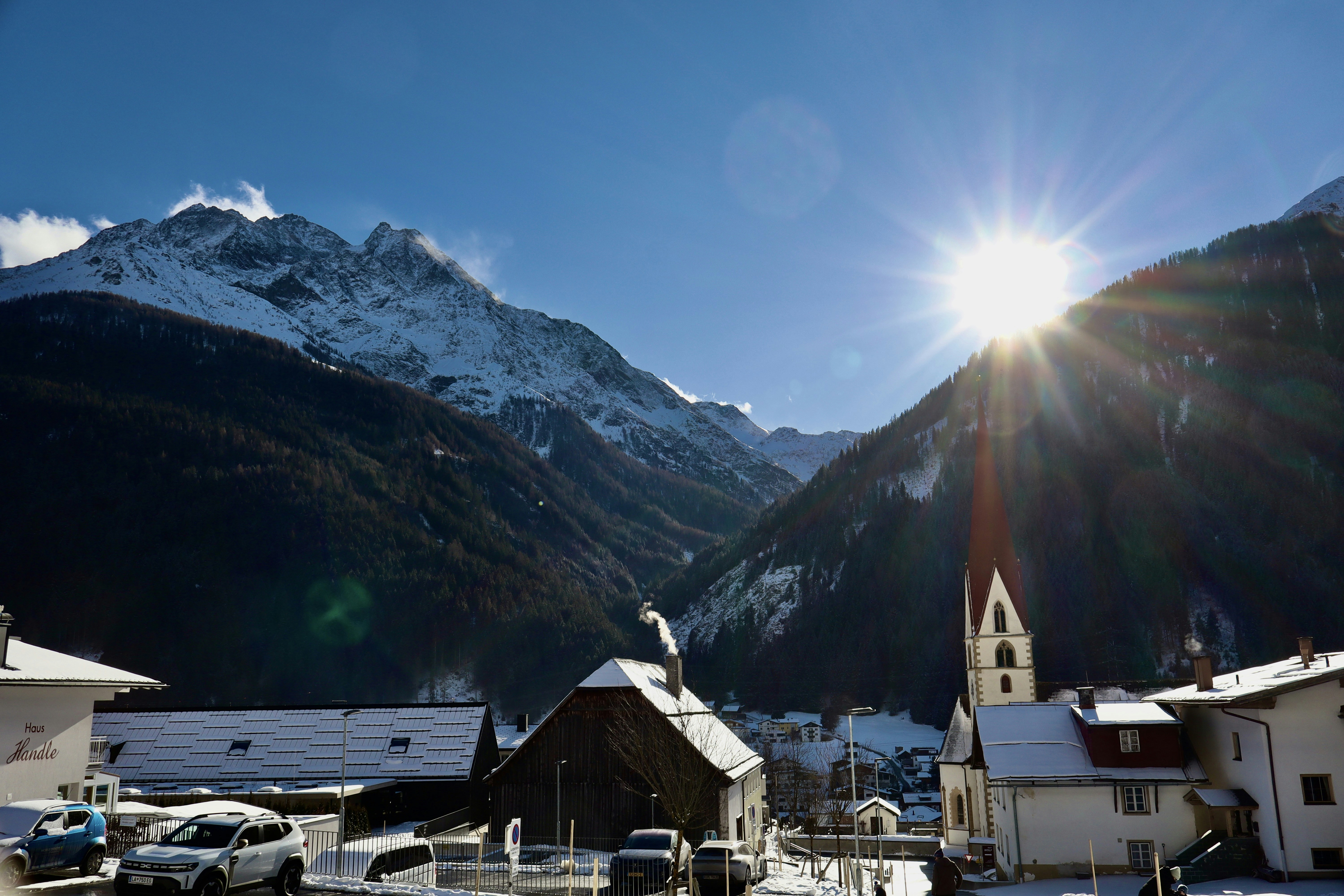Sunny mountain village with snow-covered peaks.