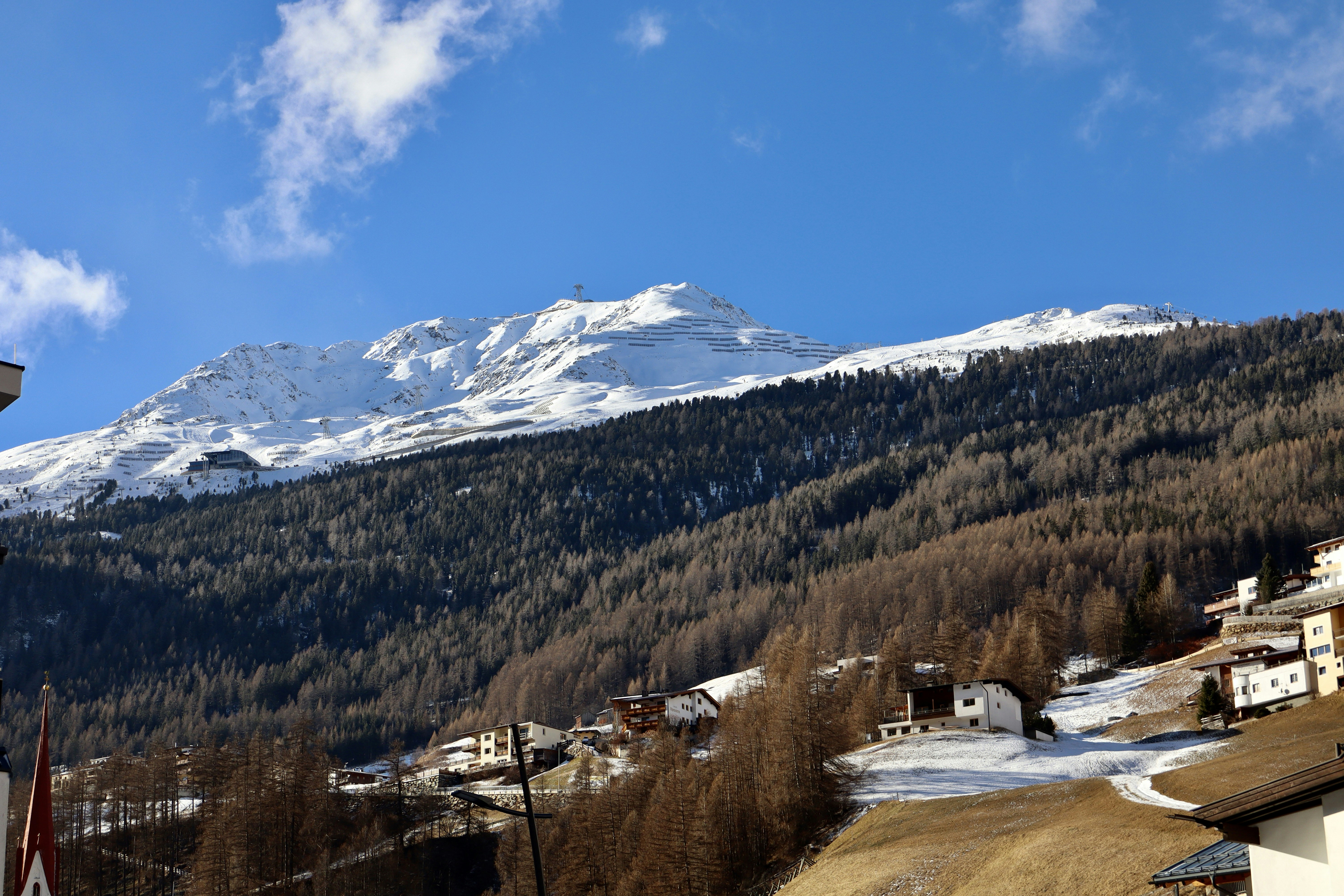 Snow-covered mountain peak above a village and village