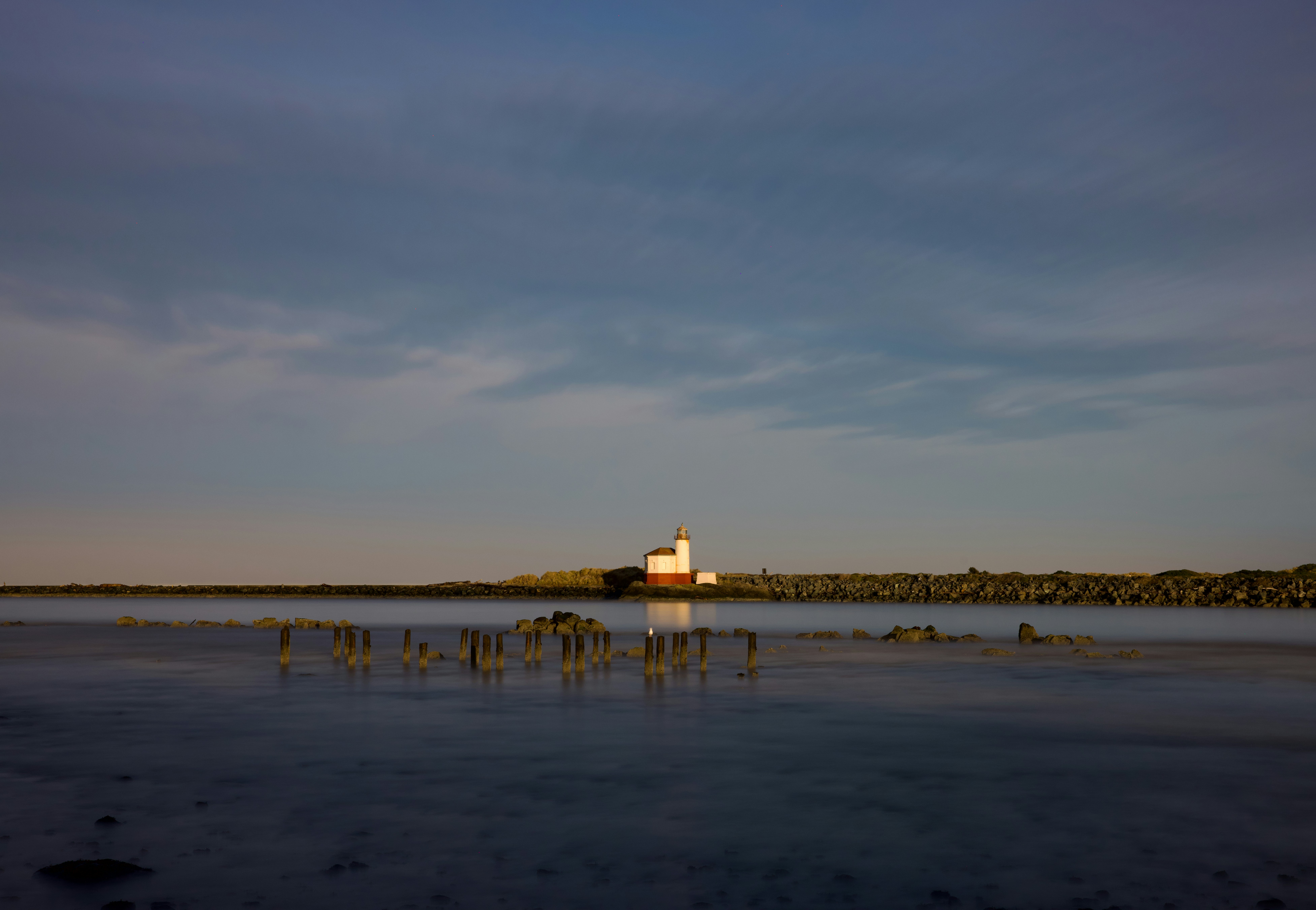 Bâtiment blanc sur une rive lointaine sous un ciel nuageux.
