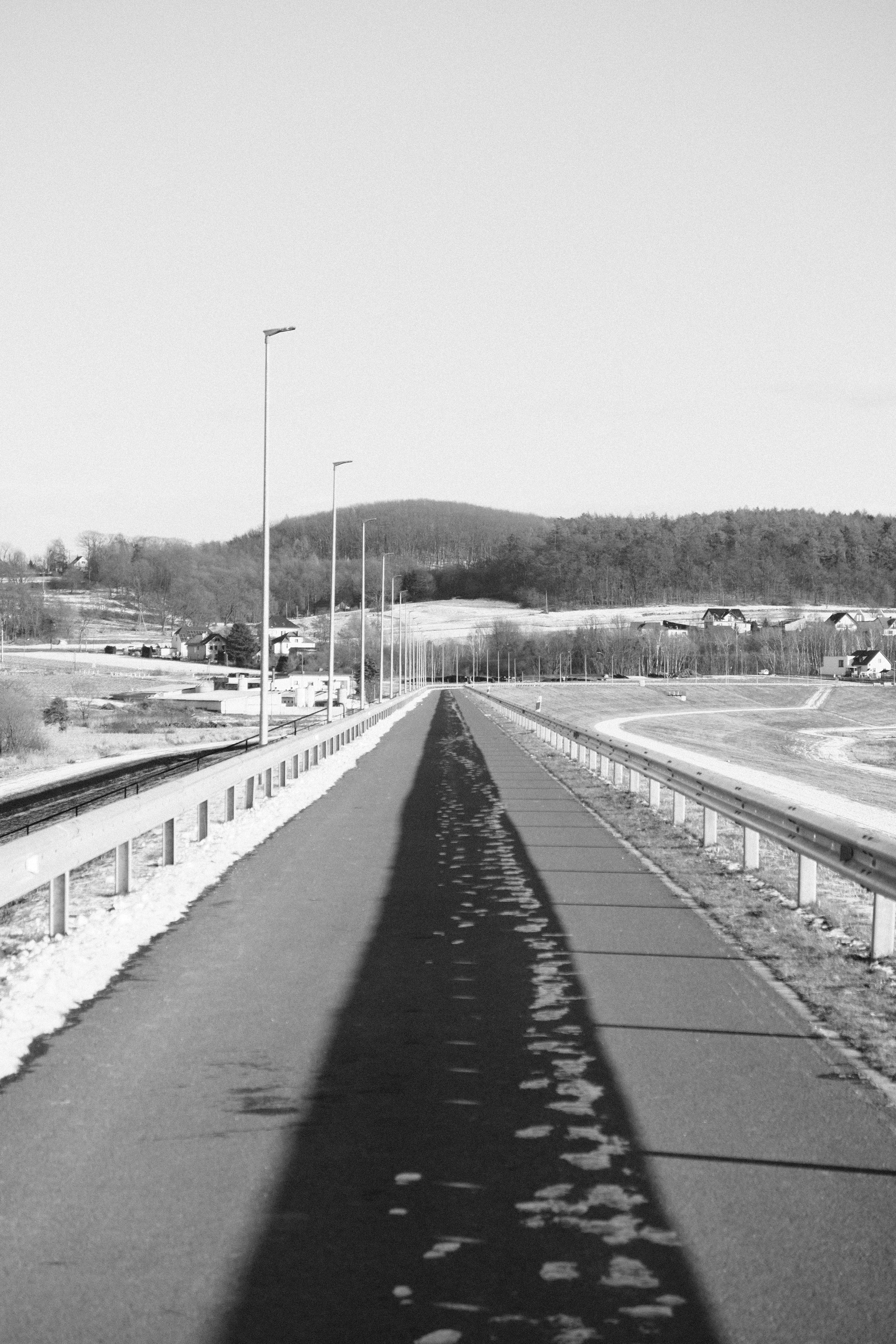 A long, straight road with streetlights and a shadow.