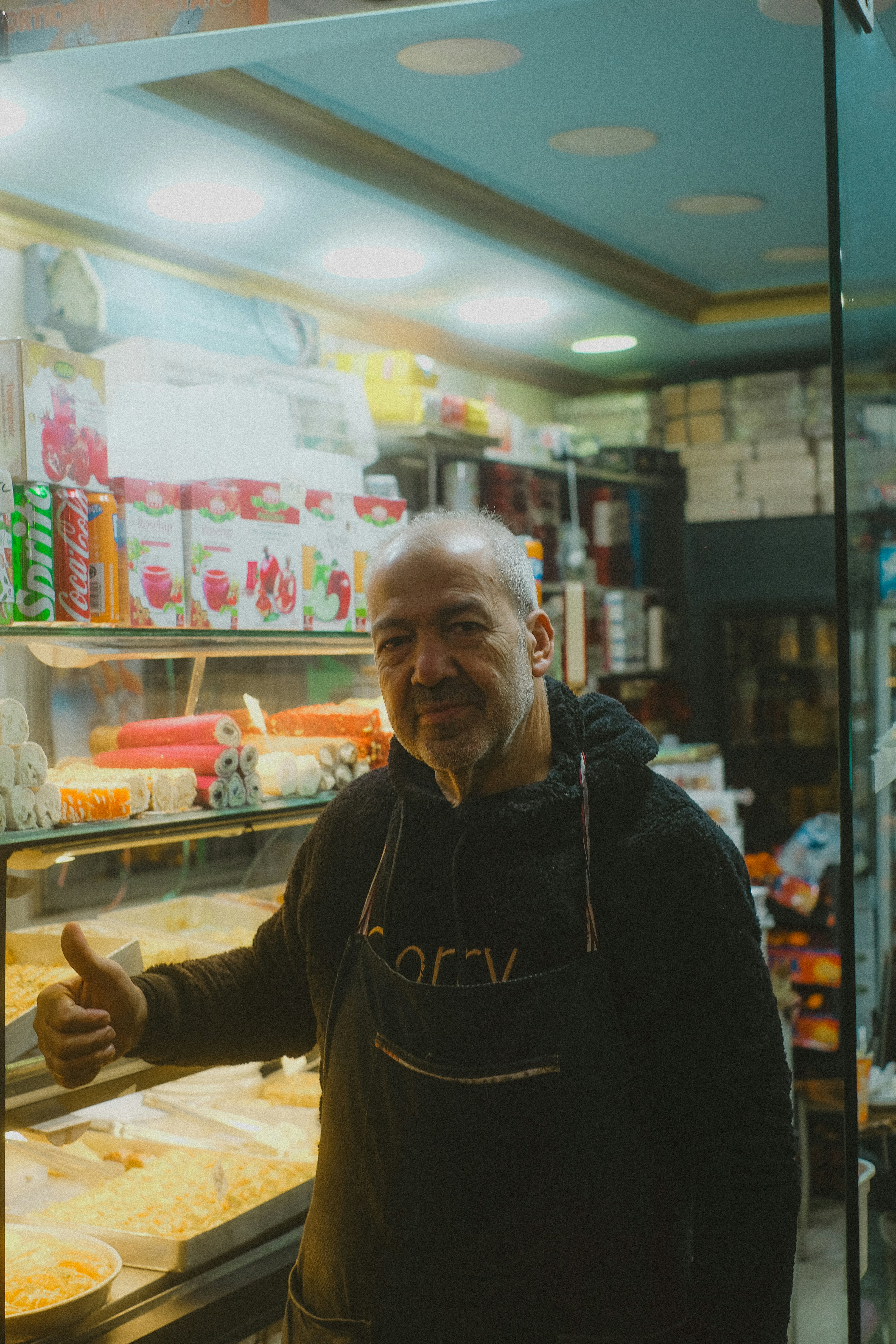 Man in apron gives thumbs up in shop