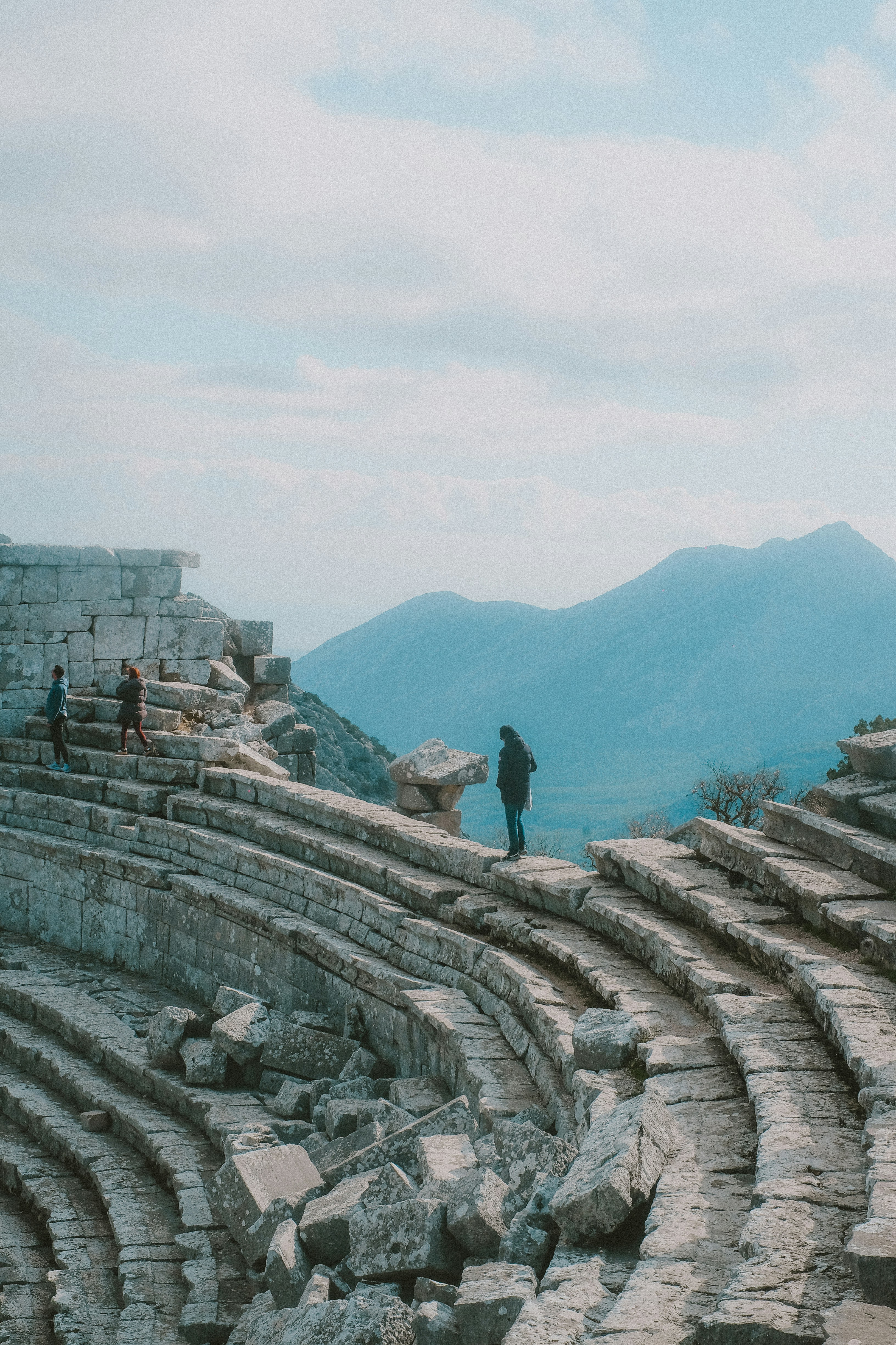 People explore ancient ruins on a mountainside.