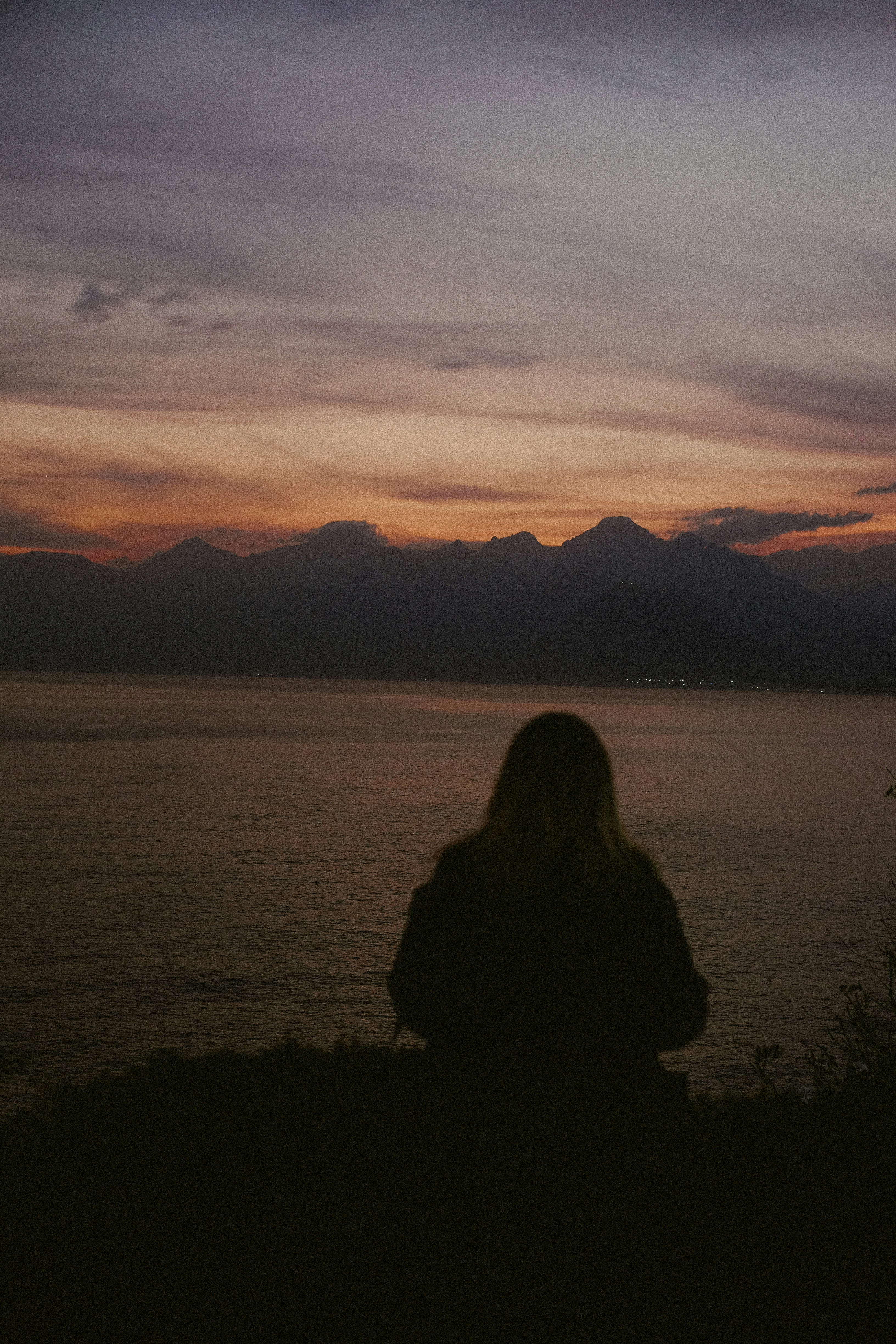 Woman watching sunset over the sea and mountains