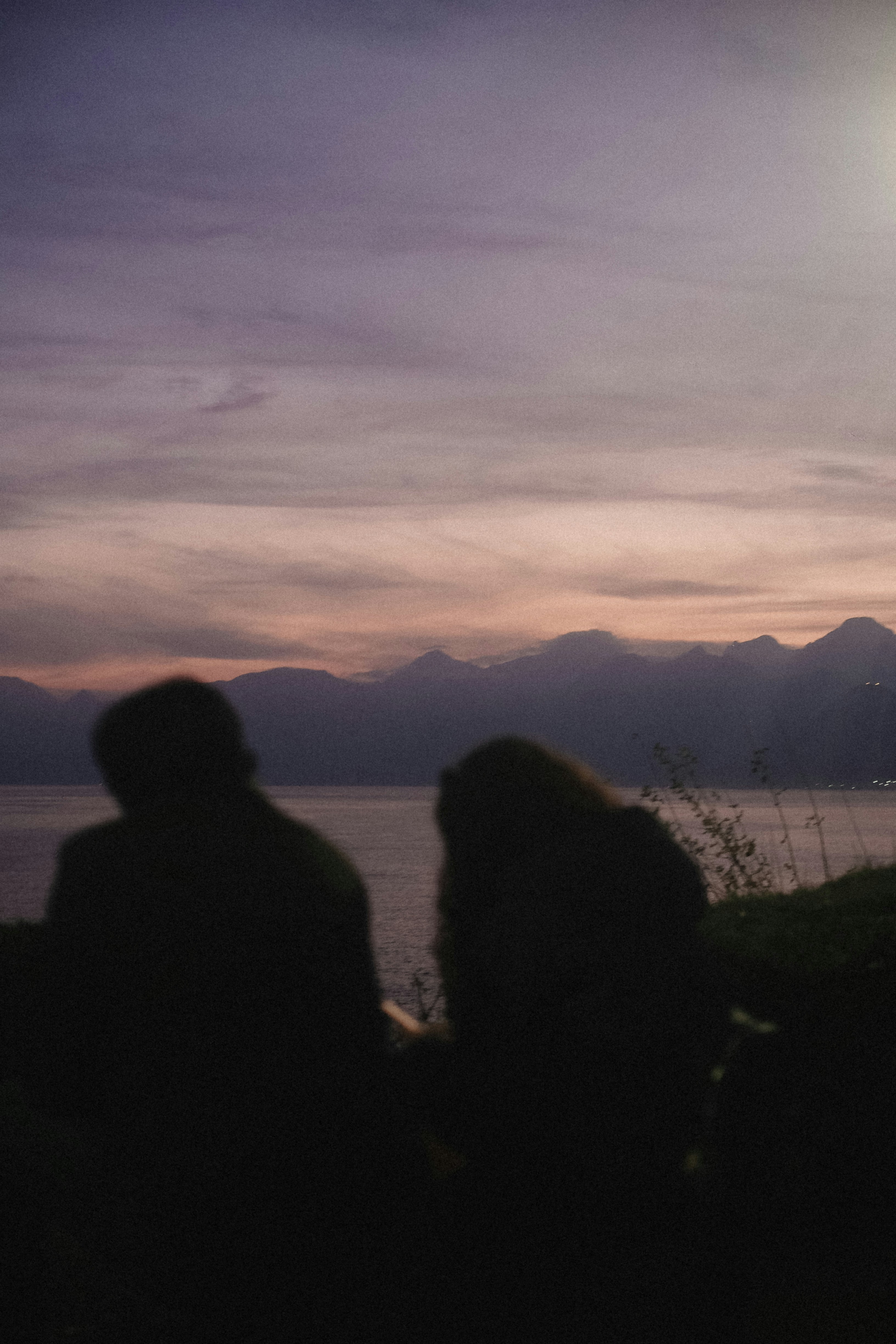 Couple watching sunset over the sea and mountains.